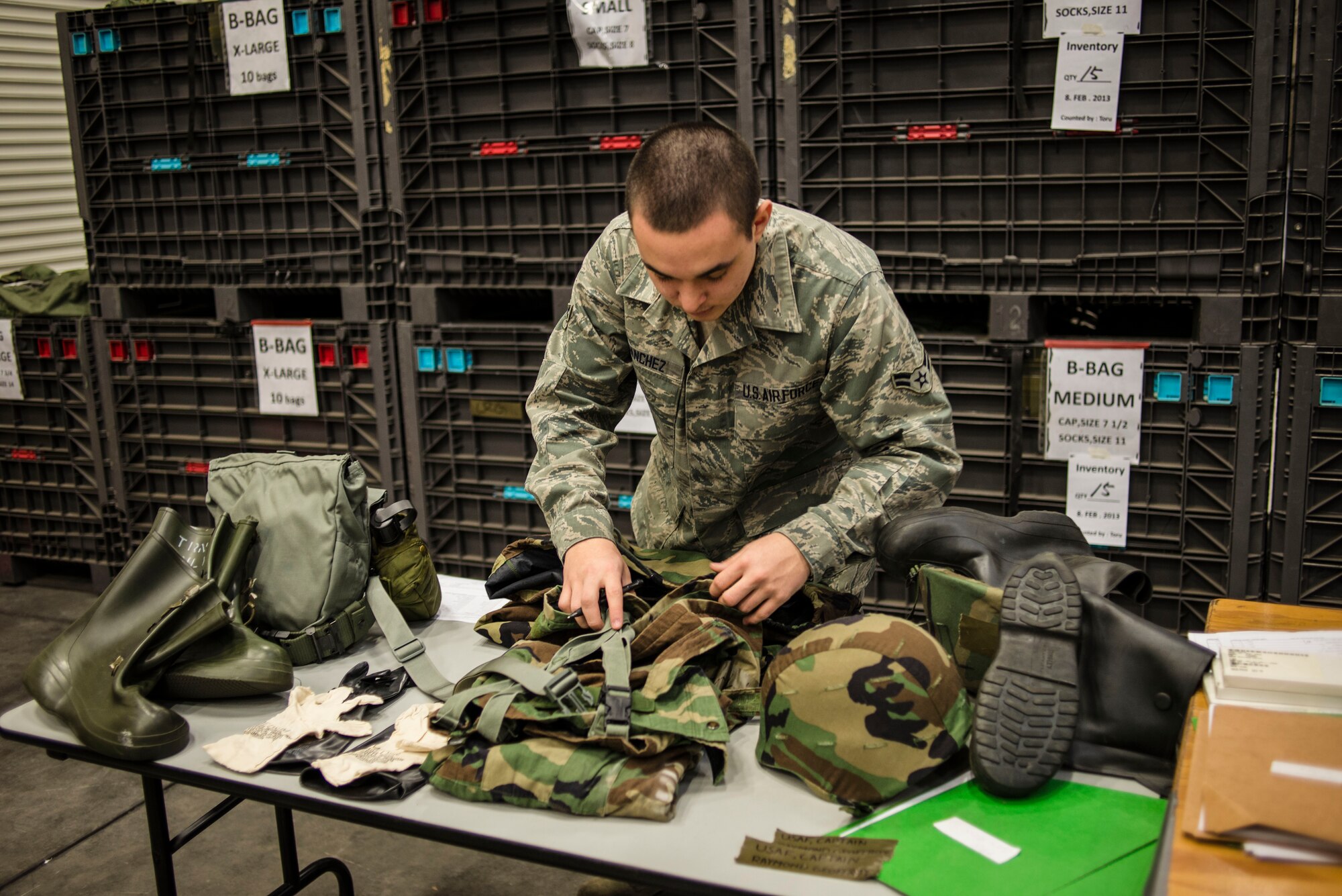 Airman 1st Class Angel Sanchez, 374th Logistics Readiness individual protective equipment technician, inspects a set of J-list chemical warfare equipment during a gear inventory and helmet issue at Yokota Air Base, Japan, Feb. 15, 2013. 374 LRS is issuing Advanced Combat Helmets to Airmen in order to improve the safety and readiness of Yokota. (U.S. Air Force photo by Capt. Raymond Geoffroy)