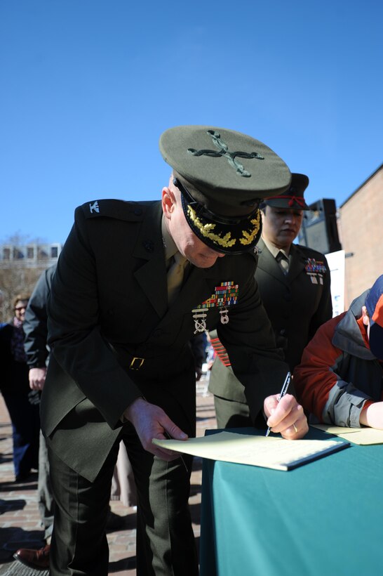 Col. David W. Maxwell, base commander, Marine Corps Base Quantico, signs the fifth annual Armed Forces Community Covenant signing at Market Square in Alexandria on Monday. Representatives from Marine Corps Base Quantico, Fort Belvoir, the Military District of Washington, the Naval Support Activity, local leaders and the public attended to support the community and military.