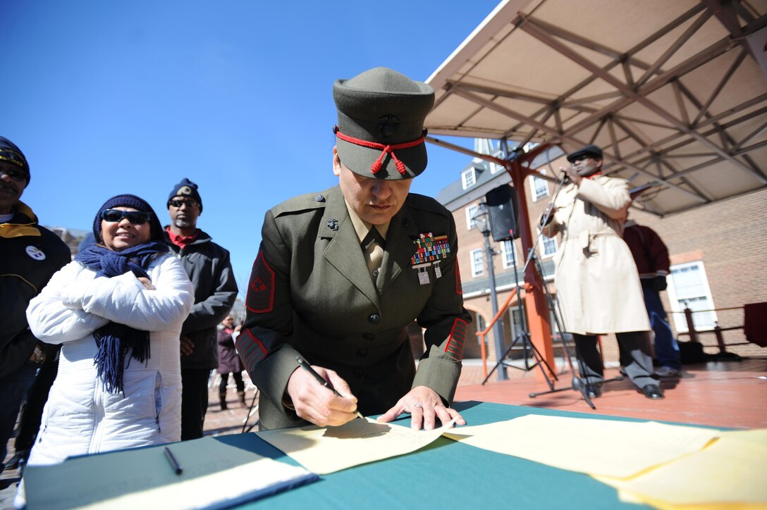 Sgt. Maj. Laura L. Brown, base sergeant major, Marine Corps Base Quantico, signs the fifth annual Armed Forces Community Covenant signing at Market Square in Alexandria on Monday. Representatives from Marine Corps Base Quantico, Fort Belvoir, the Military District of Washington, the Naval Support Activity, local leaders and the public attended to support the community and military.