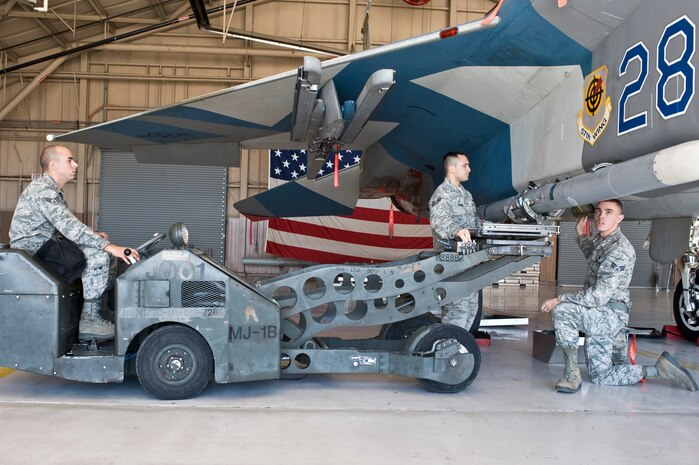 Senior Airman Christopher Wright, Staff Sgt. Joseph Ragadio, and Senior Airman Michael Schena, 57th Maintenance Group weapons load crew members, load an Aim-120C missile onto an F-15 Eagle Feb. 15, 2013, at Nellis Air Force Base, Nev. Weapons loaders work in teams of three, with the highest ranking member being the team chief. (U.S. Air Force photo by Senior Airman Matthew Lancaster)