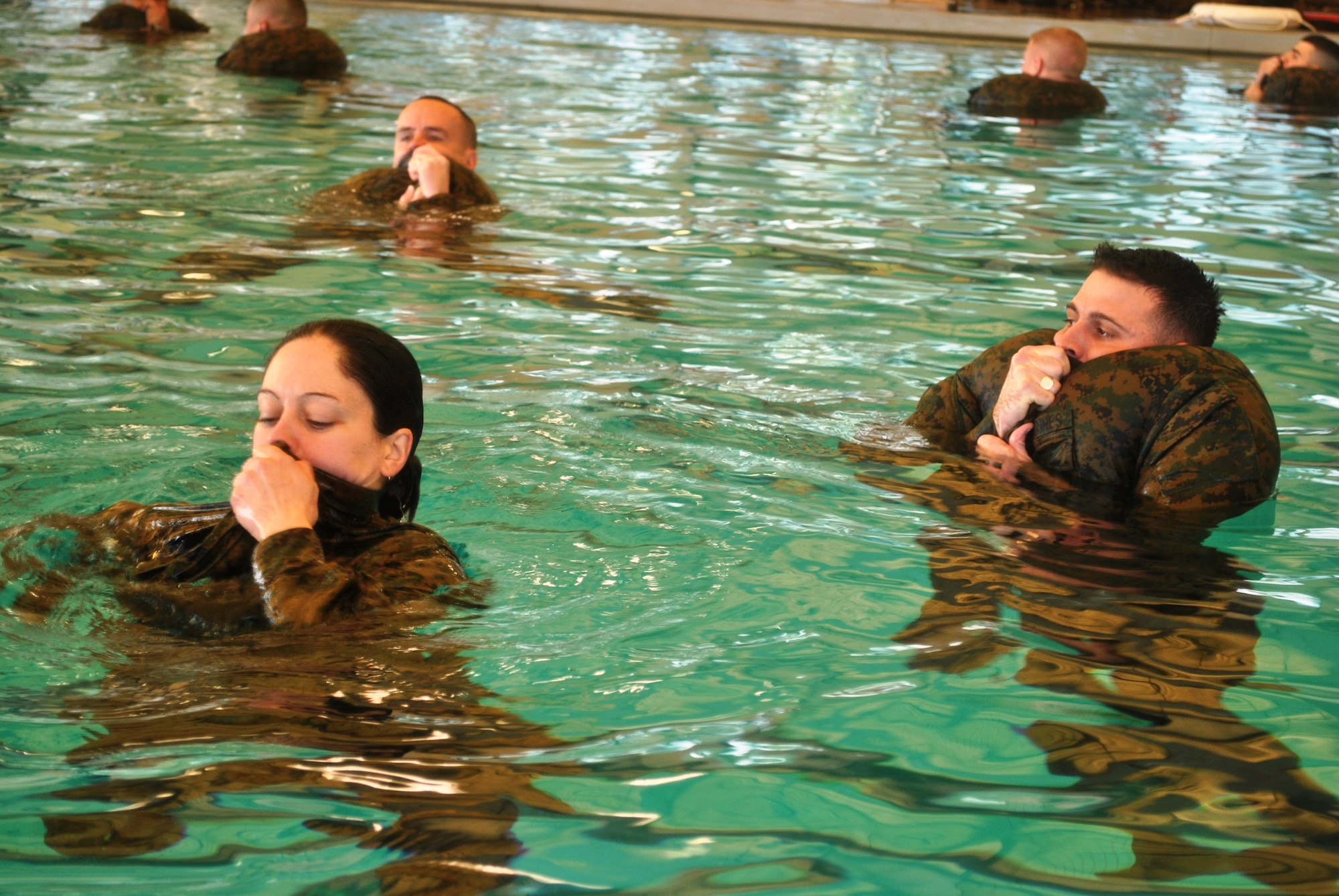 (Top left)Capt. Ryan Daly, Marine Air Group 49 intelligence officer, (right) Capt. Scott Martin, MAG-49 supply officer, and Staff Sgt. Nicole Shimp, MAG-49 intelligence NCO, practice inflating their utility blouses for use as a flotation device, Feb. 10, 2013, at Joint Base McGuire-Dix-Lakehurst, N.J. Marine Corps Combat Water Survival training teaches Marines to use their clothing or any other available materials as makeshift flotation devices while stuck out at sea. (U.S. Marine Corps photo by Cpl. David Waite/Released)