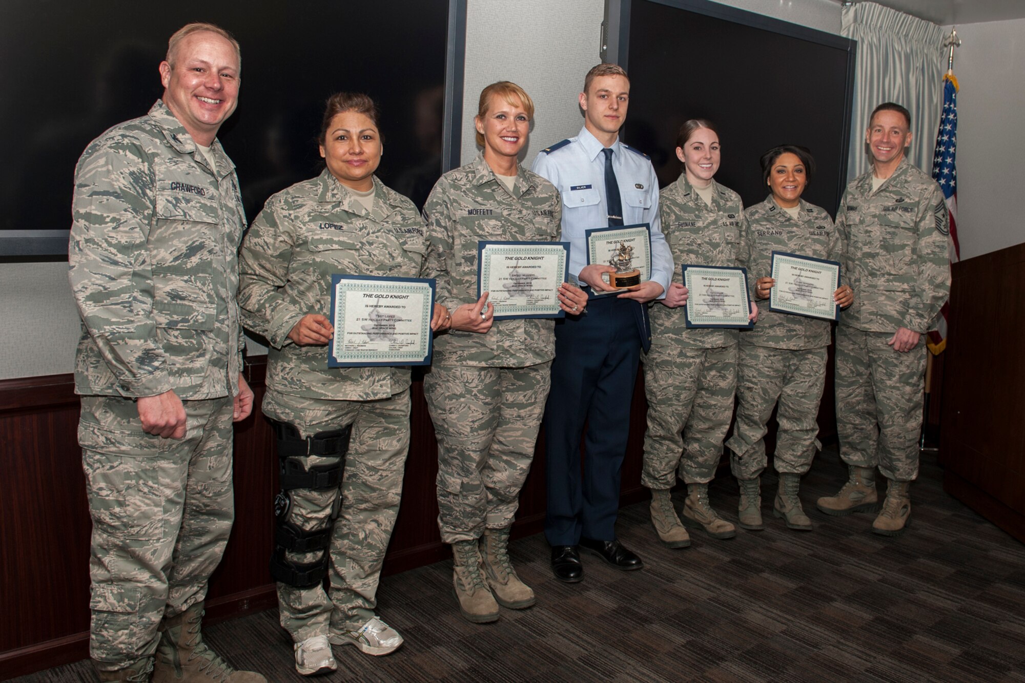 Col. Chris Crawford (left), 21st Space Wing commander, and Chief Master Sgt. Richard Redman (right), 21st SW command chief, present the Gold Knight award to the 21st SW holiday party planning team. (U.S. Air Force photo/Philip Carter)