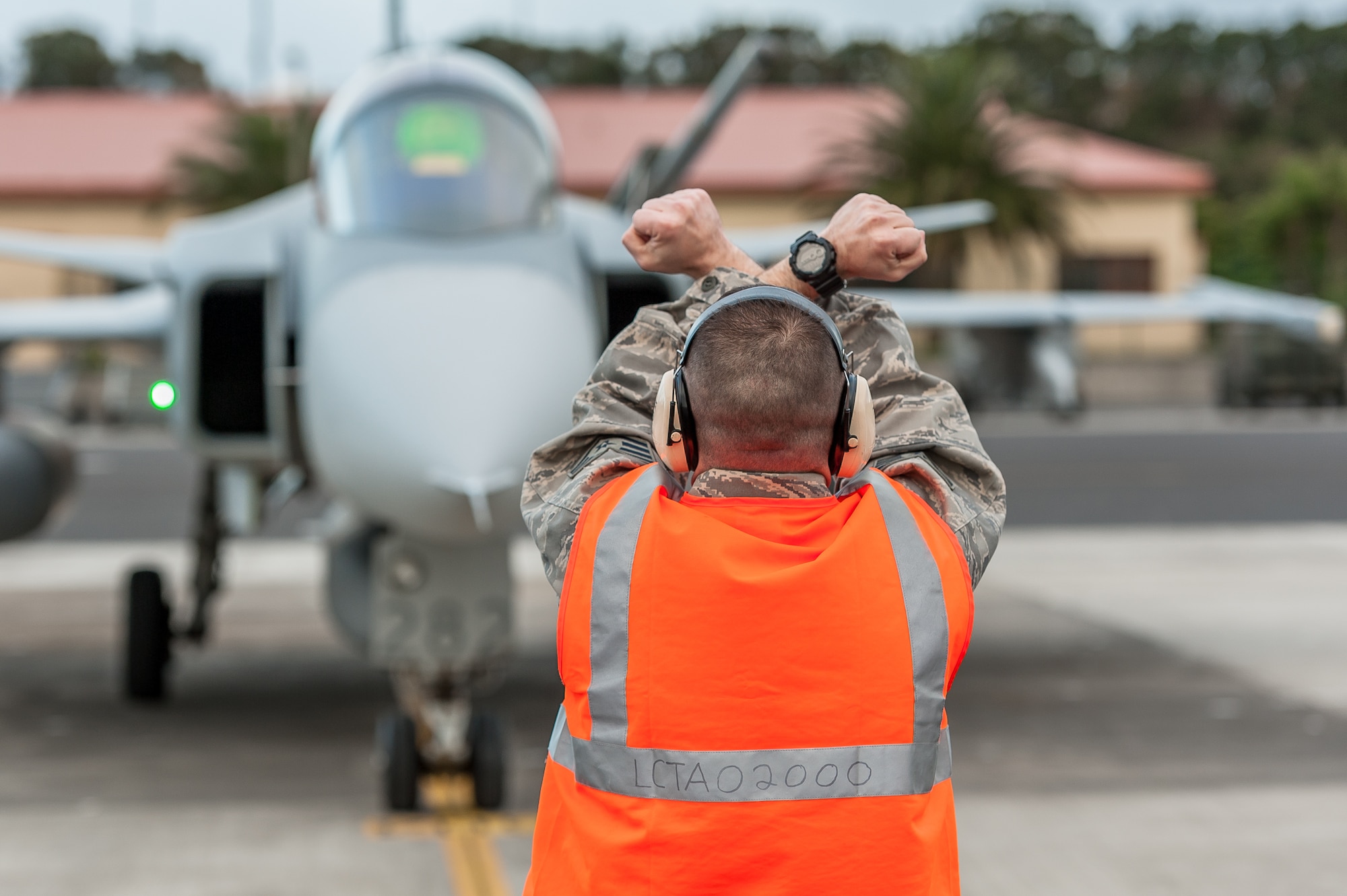 Staff Sgt. Gustavo Cifuentes, 65th Operations Support Squadron Transient Alert / Crash Recovery technician, signals a "hold" sign during the landing of the Swedish Air Force Saab JAS 39 Gripen fighter jet returning from the Red Flag aerial combat training exercise at Nellis Air Force Base, Nev., Feb. 5. (Photo by Lucas Silva)