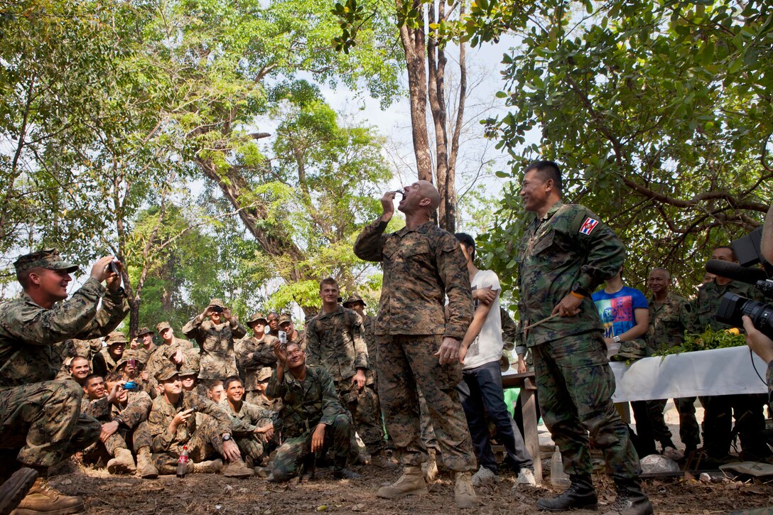 U.S. Marine Corps 1st Sgt. Joshua Clayton, center, eats a live scorpion during a jungle survival course conducted by a Thai marine during Cobra Gold 2013 in Ban Chan Krem, Chanthaburi province, Thailand, Feb. 17, 2013. 