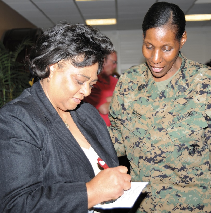 Guest speaker Shirley Sherrod, left, signs an autograph for Master Gunnery Sgt. Carlotta Moore at the Black History Month luncheon here, Feb. 12.