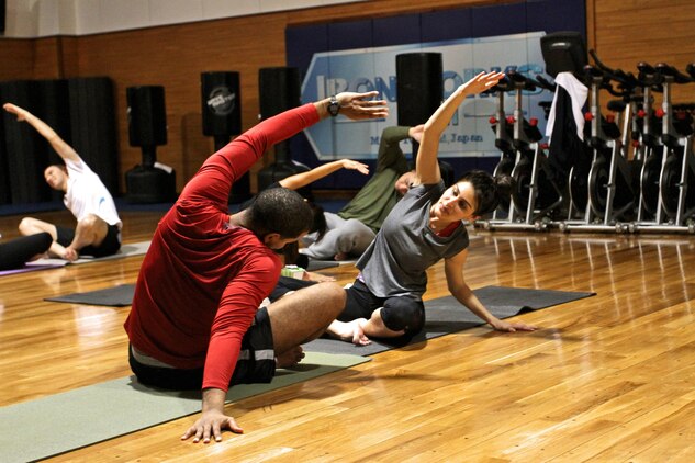 Chris Thomas and Kathy Vargas, Sweat With Your Sweetheart participants, stretch during the yoga portion of the Sweat With Your Sweetheart workout at the IronWorks Gym here, Feb. 13, 2013. Aerobics instructors found that holding the event a day early from Valentine’s day attracted more participants.