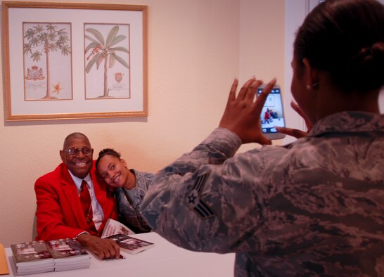 Senior Airman Ebony Owens, a 96th Logisitics Readiness Squadron equipment management technician, takes a photo for her new friend, Senior Airman Whitney Rountree, of Public Health, with Chief Master Sgt. (ret.) Walter Richardson at his book signing table after Eglin's annual National Prayer Breakfast Feb. 20. The Tuskegee Airman, guest speaker for the event, spoke to the audience about succeeding in the military with faith as documented in his memoir. (U.S. Air Force photo/Chrissy Cuttita)