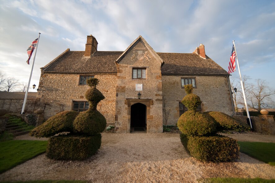 SULGRAVE, United Kingdom – Outside view of Sulgrave Manor in Sulgrave, United Kingdom. Sulgrave Manor is famous for having been the ancestral home of George Washington. The house, built in the mid-1500s, was built of local limestone, with a wide south frontage, a kitchen and buttery, a Great Hall, and above it a Great Chamber and two smaller private chambers. All these parts survive and can be seen today. The Great Hall has a stone floor, and its Tudor fireplace contains a salt cupboard carved with the initials of Lawrence Washington, the builder. Lawrence Washington, a Northampton wool-trader, is the great-great-great-great-great grandfather of George Washington. The Washington’s held the house for more than one hundred years. (U.S. Air Force photo by Staff Sgt. Brian Stives)
