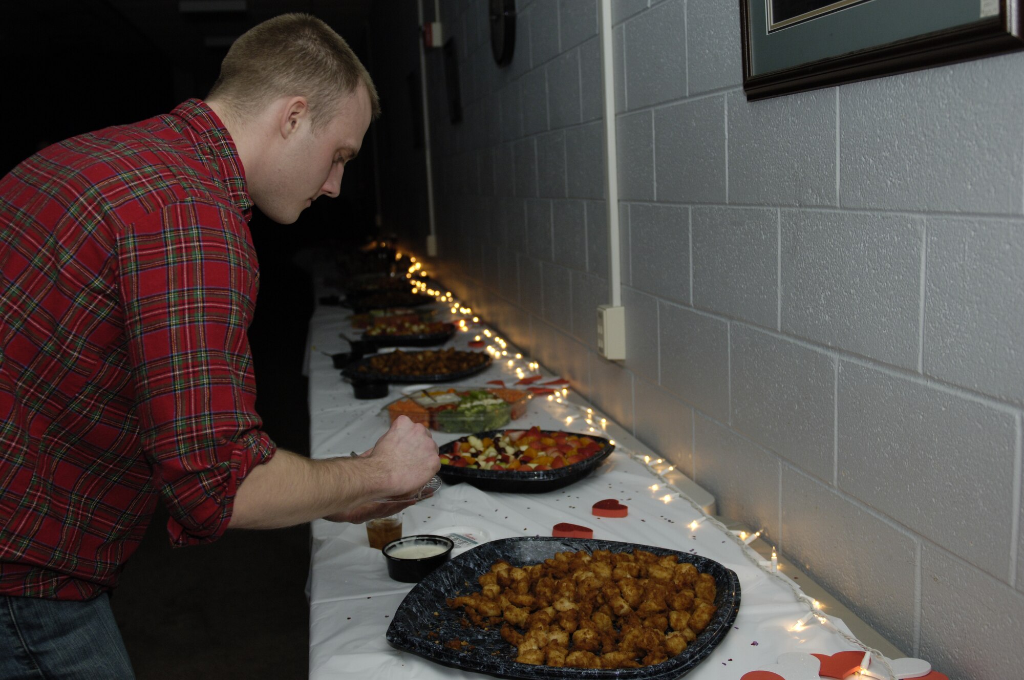 U.S. Air Force Airman 1st Class Mike Hegarty, 1st Operations Support Squadron air traffic controller gathers a snack in the Langley Community Center at Langley Air Force Base Va., Feb. 16, 2013. Hegarty is the secretary of Airmen Committed to Excellence, the organization that hosted the Valentine’s party for junior enlisted Airmen. (U.S. Air Force photo by Airman Kimberly Nagle/Released)  