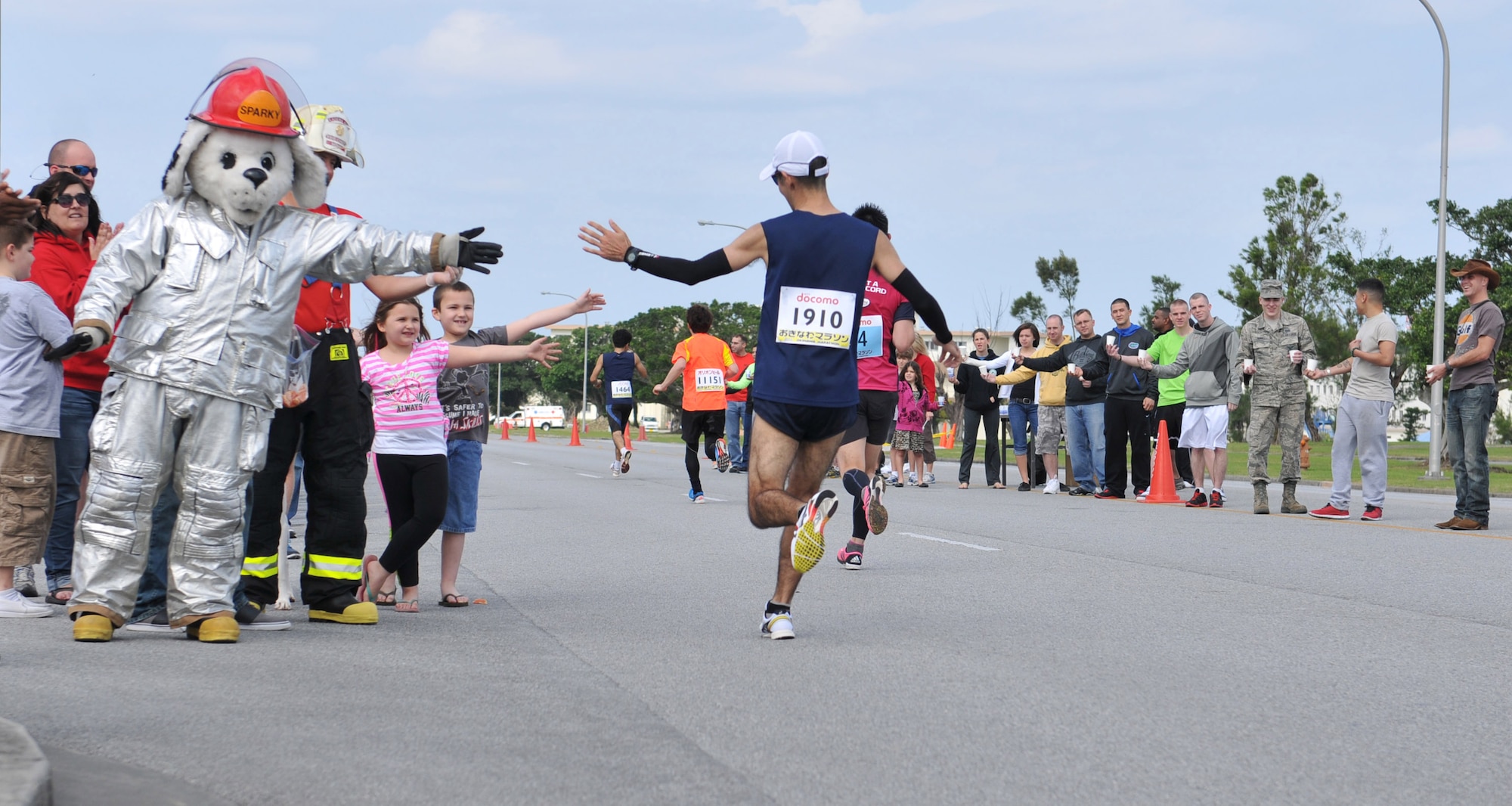 A participant of the 2013 Okinawa Marathon high-fives volunteers on Kadena Air Base, Japan, Feb. 17, 2013. More than 500 volunteers came out to the event to hand out water, food and cheer on runners on during the 2.8-km stretch through the base. Sparky, 18th Civil Engineer Group mascot, along with firefighters showed their support for the runners. (U.S. Air Force photo/Airman 1st Class Keith A. James)
