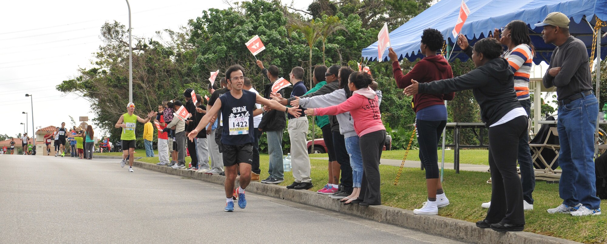 Runners entering Kadena's Gate 2 high-five volunteers during the 2013 Okinawa Marathon on Kadena Air Base, Japan, Feb.17, 2013. More than 11,000 runners, including more than 160 service members from around the island, participated in the Okinawa Marathon with a 78 percent completion rate. (U.S. Air Force photo/Airman 1st Class Keith A. James)