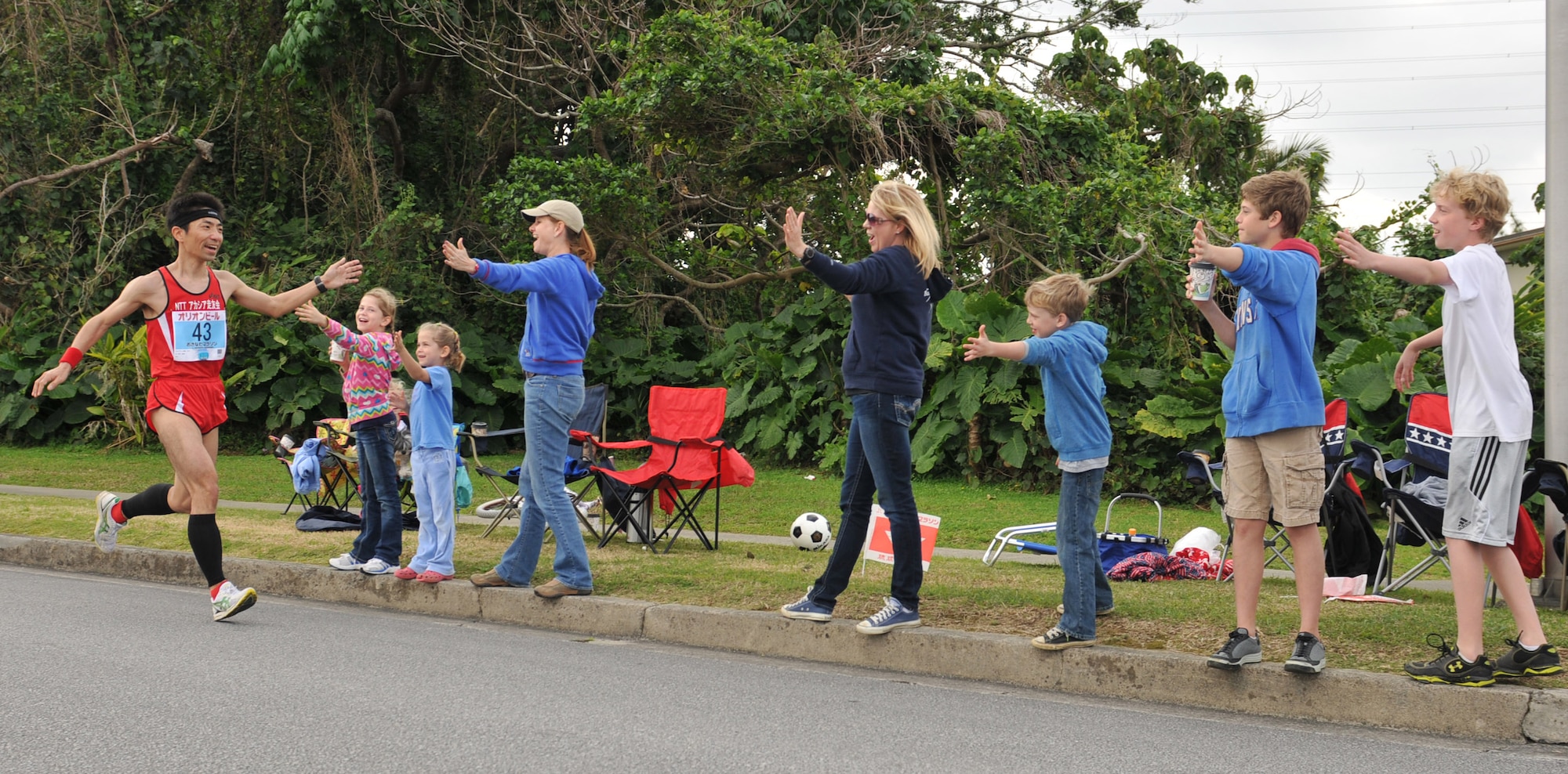 A family of volunteers stick out their hands for high-fives during the 2013 Okinawa Marathon on Kadena Air Base, Japan, Feb. 17, 2013. Kadena has supported the Okinawa Marathon for 21 years with hundreds of volunteers each year. (U.S. Air Force photo/Airman 1st Class Keith A. James)
