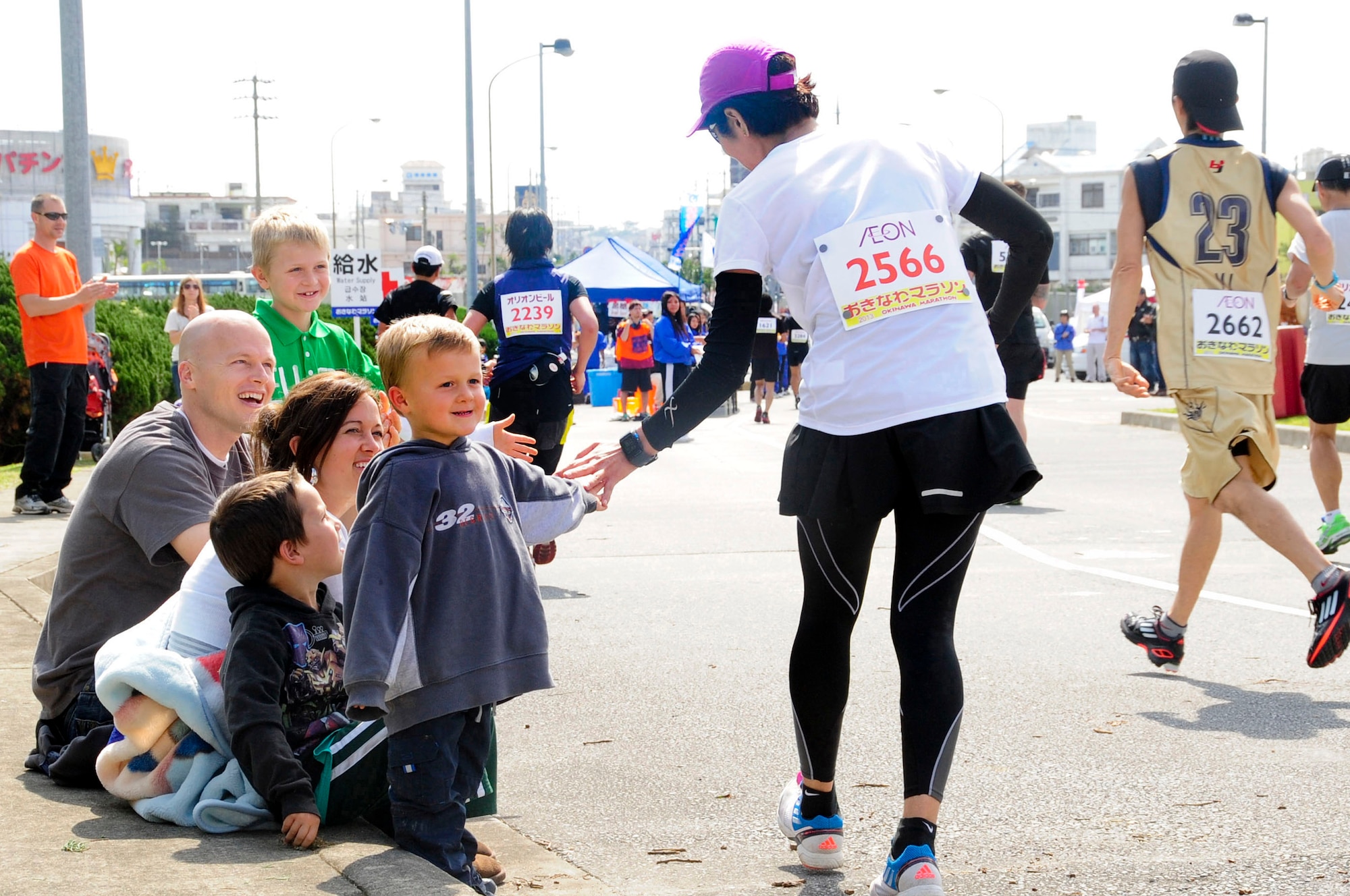 A family high-fives and cheers on runners as they exit Kadena's Gate 5, finishing the base's portion of the 2013 Okinawa Marathon on Kadena Air Base, Japan, Feb. 17, 2013. For 21 years, Kadena has supported the Okinawa Marathon with volunteers and provided a portion of the route for the runners. (U.S. Air Force photo/Staff Sgt. Darnell T. Cannady)