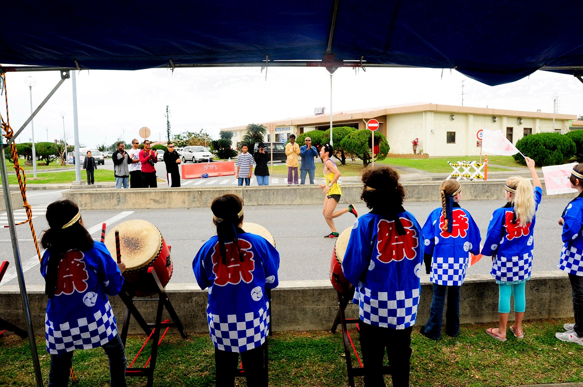 A participant of the 2013 Okinawa Marathon runs through a cheering crowd on Kadena Air Base, Japan, Feb. 17, 2013. More than 500 base volunteers handed out water and cheered on participants before they made their way out Kadena's Gate 5 towards the final stretch of the marathon. This is the 21st year Kadena has supported the Okinawa Marathon. (U.S. Air Force photo/Staff Sgt. Darnell T. Cannady) 