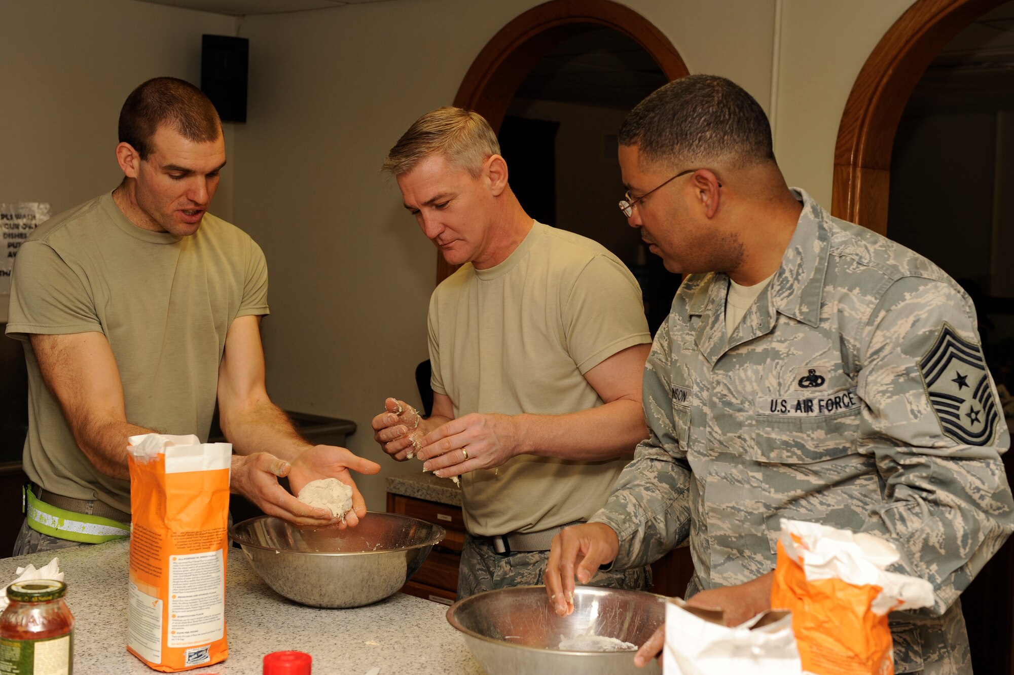 Staff Sgt. Jeffery Furbush, 8th Maintenance Squadron, demonstrates how to make pizza dough to Col. John Pearse, 8th Fighter Wing commander, Chief Master Sgt. Phillip Robinson, 8th FW command chief, at Kunsan Air Base, Republic of Korea, Feb. 20, 2013. This program has been encouraging Airmen to learn healthy cooking techniques for ten years.  (U.S. Air Force photo by Senior Airman Marcus Morris/Released)