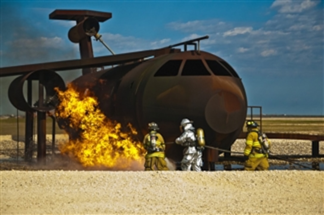 Firefighters from Laughlin Air Force Base and Del Rio Fire departments move in to extinguish a ground fire next to an aircraft mock up during a training exercise at Laughlin Air Force Base, Texas, on Feb. 11, 2013.  The exercise is designed to help Del Rio firefighters maintain their currencies while training alongside Air Force firefighters. 