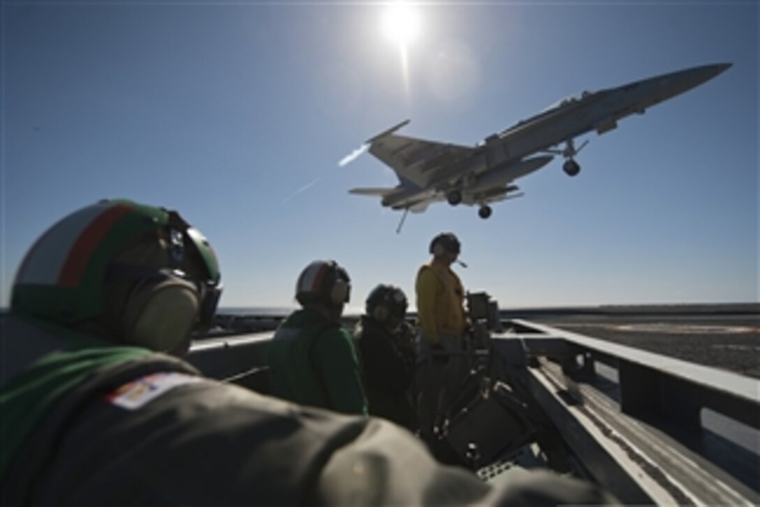 Flight deck crewmen watch as an F/A-18C Hornet aircraft prepares to land aboard the aircraft carrier USS Carl Vinson (CVN 70) as the ship conducts flight operations in the Pacific Ocean on Feb. 13, 2013.  The Carl Vinson is under way to conduct precision approach landing system and flight deck certifications.  