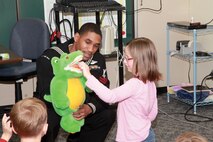 Petty Officer 2nd Class Henry B. Shaw holds a stuffed alligator for Shawna Shobe while she brushes its teeth during a presentation for a second-grade class Feb. 12 at Kinser Elementary School. Shaw is a member of a group of volunteers who are visiting elementary schools on military installations throughout Okinawa in February, which is National Children's Dental Health Month. Sailors educated students on which foods and drinks to avoid and proper brushing and flossing techniques to maintain good dental hygiene. Shaw is a hospital corpsman with 3rd Dental Battalion, 3rd Marine Logistics Group, III Marine Expeditionary Force. Shobe is a second-grade student at Kinser Elementary School.