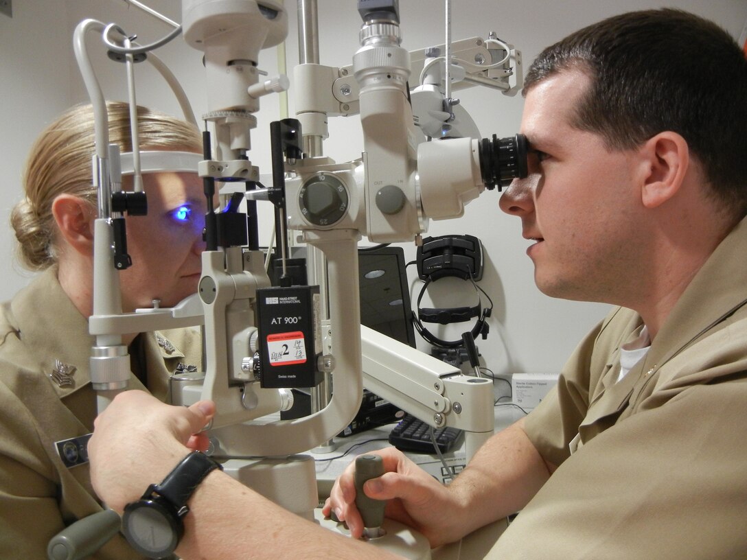Navy Lt. Adam Preston, head of the Optometry Department at Naval Health Clinic Quantico, right, checks Petty Officer 1st Class’ eyes at the clinic. 