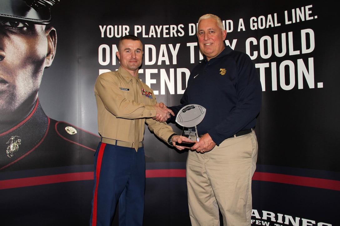 Recruiting Station Twin Cities Commanding Officer Maj. Kenneth Gawronski presents the Semper Fidelis Coach Award to Jeff Ferguson at the Minneapolis Glazier Clinic Feb. 16. Ferguson has served as a member of the Totino-Grace football coaching staff for the past 15 years, 11 as the head coach. His overall record is 129-13. In 2009, the Minnesota Football Coaches Association named him the Class 4A coach of the year.