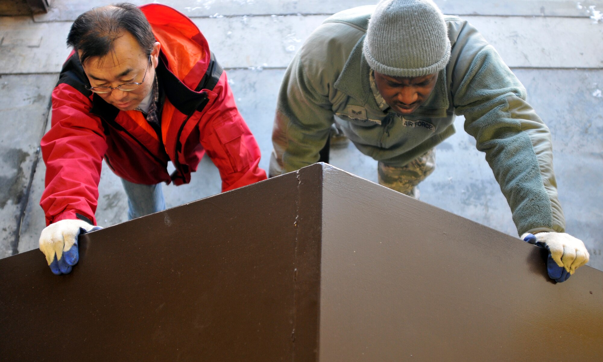 Hajime Sasaki, 35th Civil Engineer Squadron solid waste manager, and U.S. Air Force Senior Airman David Washington, 35 CES recycling manager, push a large cardboard collection trailer into a building to warm it at Misawa Air Base, Japan, Feb. 11, 2013. The trailer, was full of frozen cardboard, which made it extremely hard to get out. The recycling center is located by the base veterinarian’s office. (U.S. Air Force photo by Tech. Sgt. Phillip Butterfield)