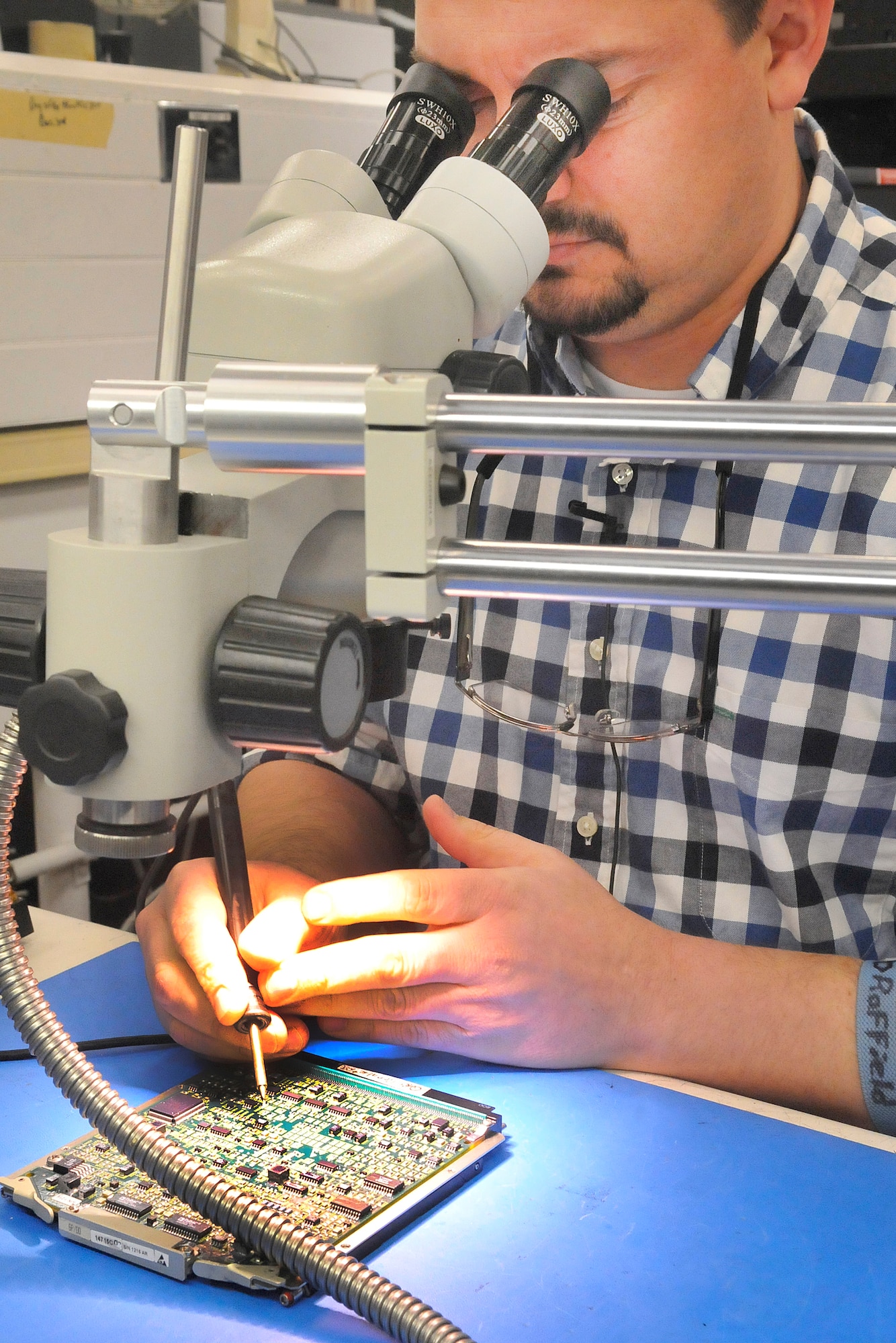 Steve Raffield, integrated electronics systems mechanic, uses a microscope to solder components on a circuit card for the electronic unit processor for the Joint Helmet Mounted Cueing System. (U. S. Air Force photo/Sue Sapp)