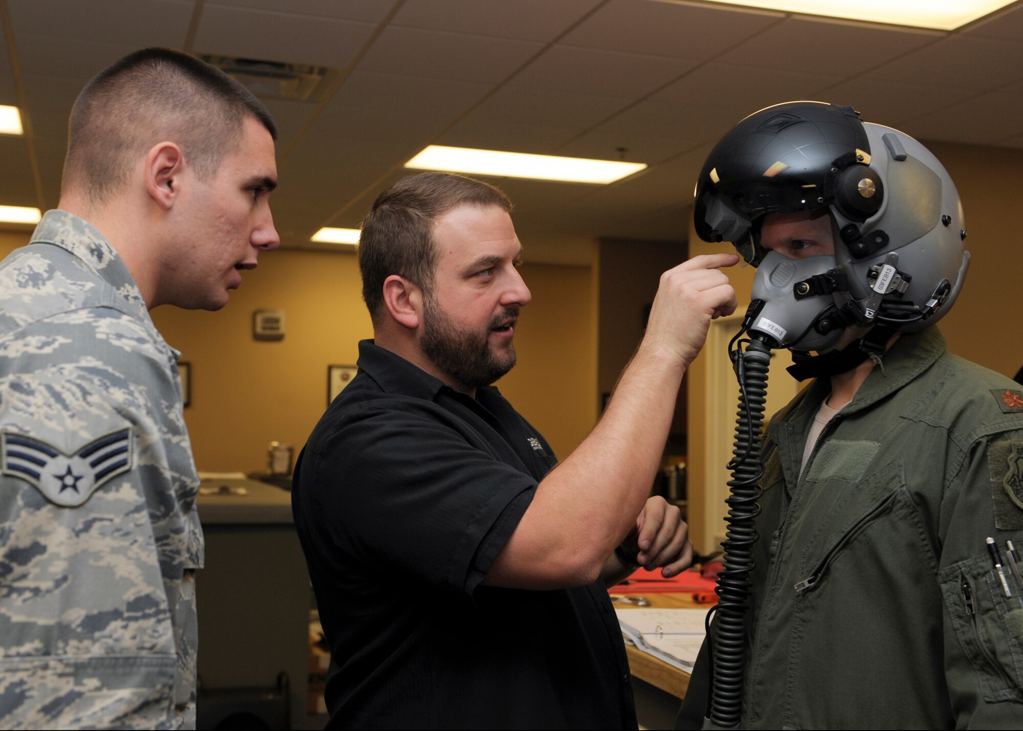 U.S. Air Force Senior Airman David Hainley (left), 23d Operations Support Squadron aircrew flight equipment technician , listens as Scott Smither (center), GENTEX® Corporation technical specialist, discusses features of the Helmet Mounted Cueing System as  Maj. Gage Evert, 74th Fighter Squadron A-10C Thunderbolt II pilot, is fitted for one at Moody Air Force Base, Ga., Jan. 17, 2013. Smither, along with other advisors of the HMCS, came to the base to instruct the 23d OSS Airmen on how to individually fit and maintain the systems. (U.S. Air Force photo by Senior Airman Eileen Meier/Released) 