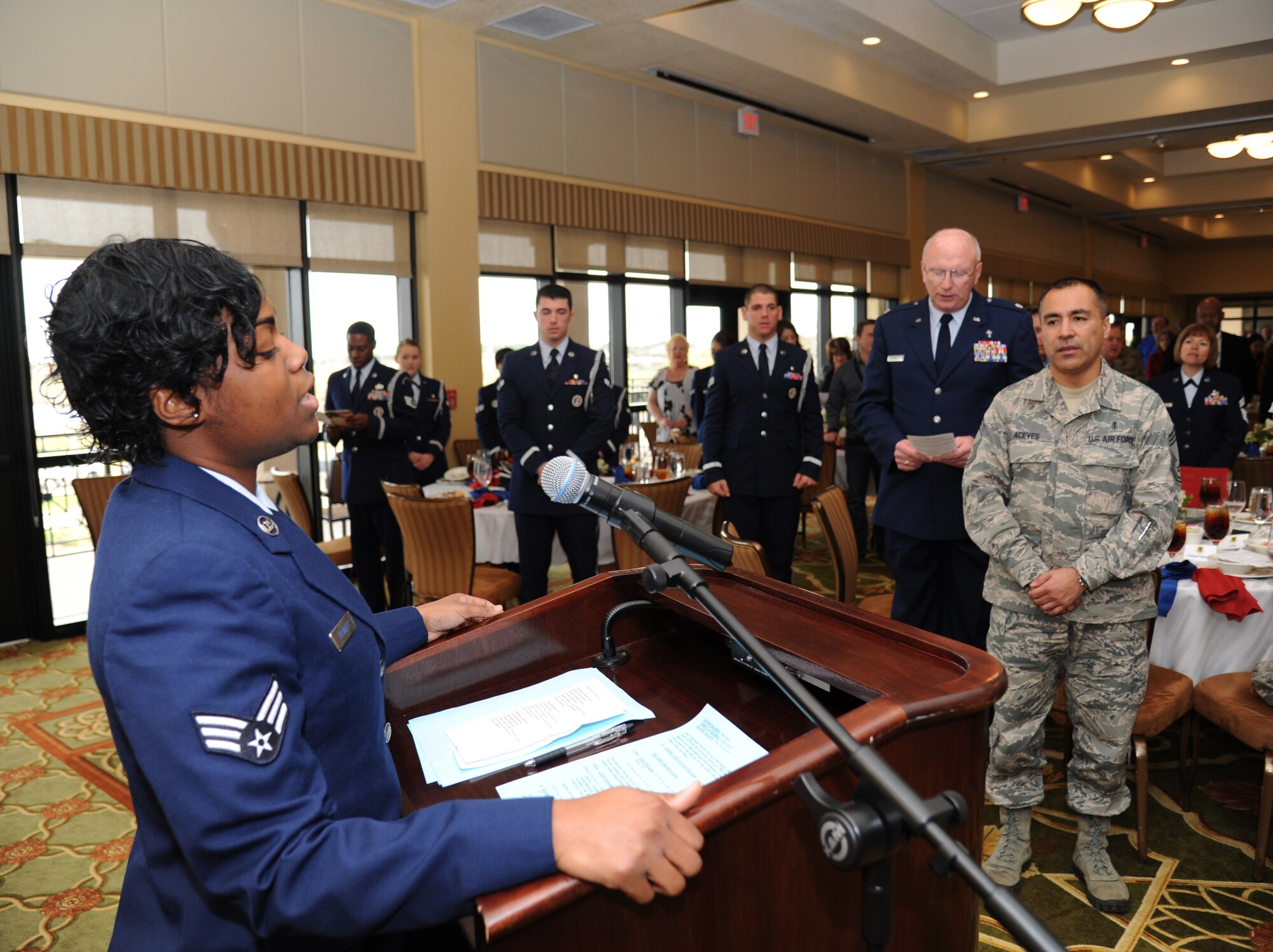 Senior Airman Nicole Rambert, 81st Surgical Operations Squadron, leads the audience in the singing of “America The Beautiful” at the National Prayer Luncheon Feb. 20, 2013, at the Bay Breeze Event Center, Keesler Air Force Base, Miss.  The event included a ceremony by the Keesler Honor Guard to honor prisoners of war and those missing in action and guest speaker, retired Col. Richard Toliver. The annual event, a tradition that stems back to President Dwight D. Eisenhower in 1953, allows individuals of different faiths and backgrounds to join together to reflect and develop their spiritual fitness. This year’s theme was “Pray for America.”  (U.S. Air Force photo by Kemberly Groue)