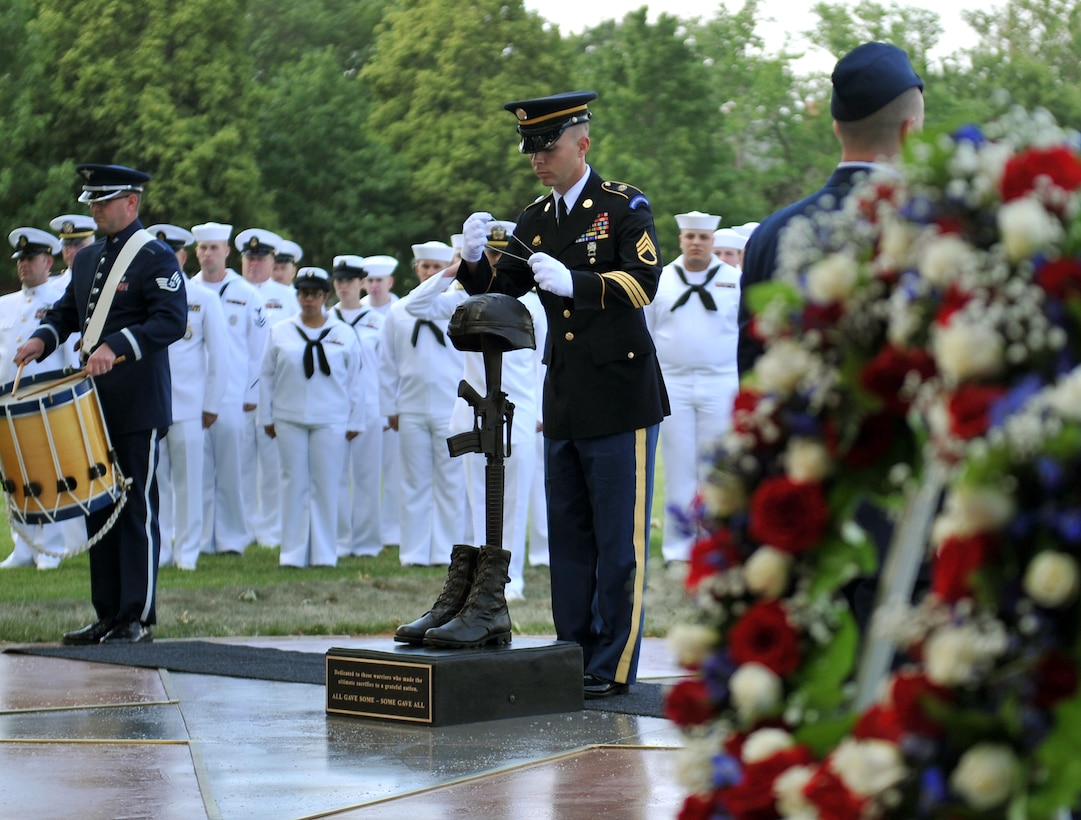 Staff Sergeant Jarrett Robinett performs a ceremonial drum roll during the placement of dog tags at the Fallen Warrior Memorial statue at Offutt AFB NE.