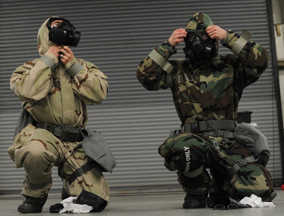 Airman 1st Class Ryan O'Keefe, 11th Civil Engineer Squadron heavy equipment operator and Staff Sgt. Joseph Romero, 11th Command Post senior controller, changes into Mission Oriented Protective Posture (MOPP) Level four during a Chemical, Biological, Radiological and Nuclear Defense (CBRN) Survival Skills Training course on Joint Base Andrews, Md., Feb. 14, 2013. The students have a goal of one minute to go from MOPP level two to four. (U.S. Air Force photo/Airman 1st Class Nesha Humes)(Released)