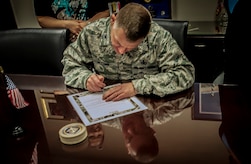 Colonel Richard McComb, Joint Base Charleston commander, signs the seventh annual Military Saves Campaign pledge to commemorate Military Saves Week in his office, Feb. 13, 2013, at Joint Base Charleston – Air Base, S.C.  Military Saves Week is Feb. 25 through March 2, 2013. (U.S. Air Force photo / Airman 1st Class Tom Brading)