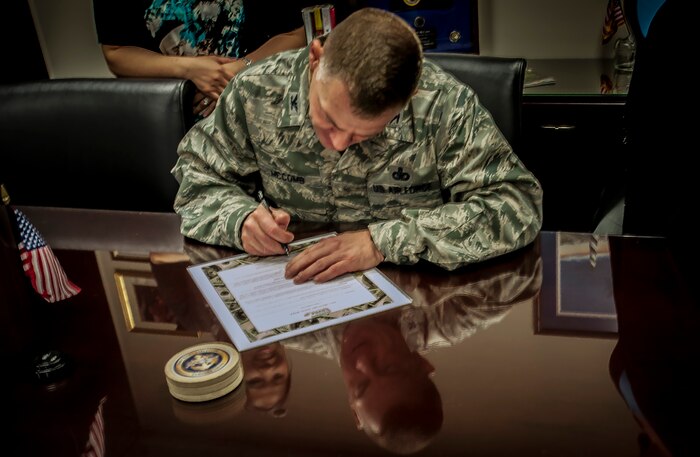 Colonel Richard McComb, Joint Base Charleston commander, signs the seventh annual Military Saves Campaign pledge to commemorate Military Saves Week in his office, Feb. 13, 2013, at Joint Base Charleston – Air Base, S.C.  Military Saves Week is Feb. 25 through March 2, 2013. (U.S. Air Force photo / Airman 1st Class Tom Brading)