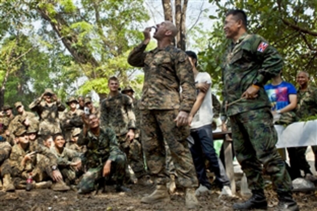 U.S. Marine Corps 1st Sgt. Joshua Clayton, center, eats a live scorpion during a jungle survival course conducted by a Thai marine during Cobra Gold 2013 in Ban Chan Krem, Chanthaburi province, Thailand, Feb. 17, 2013. 