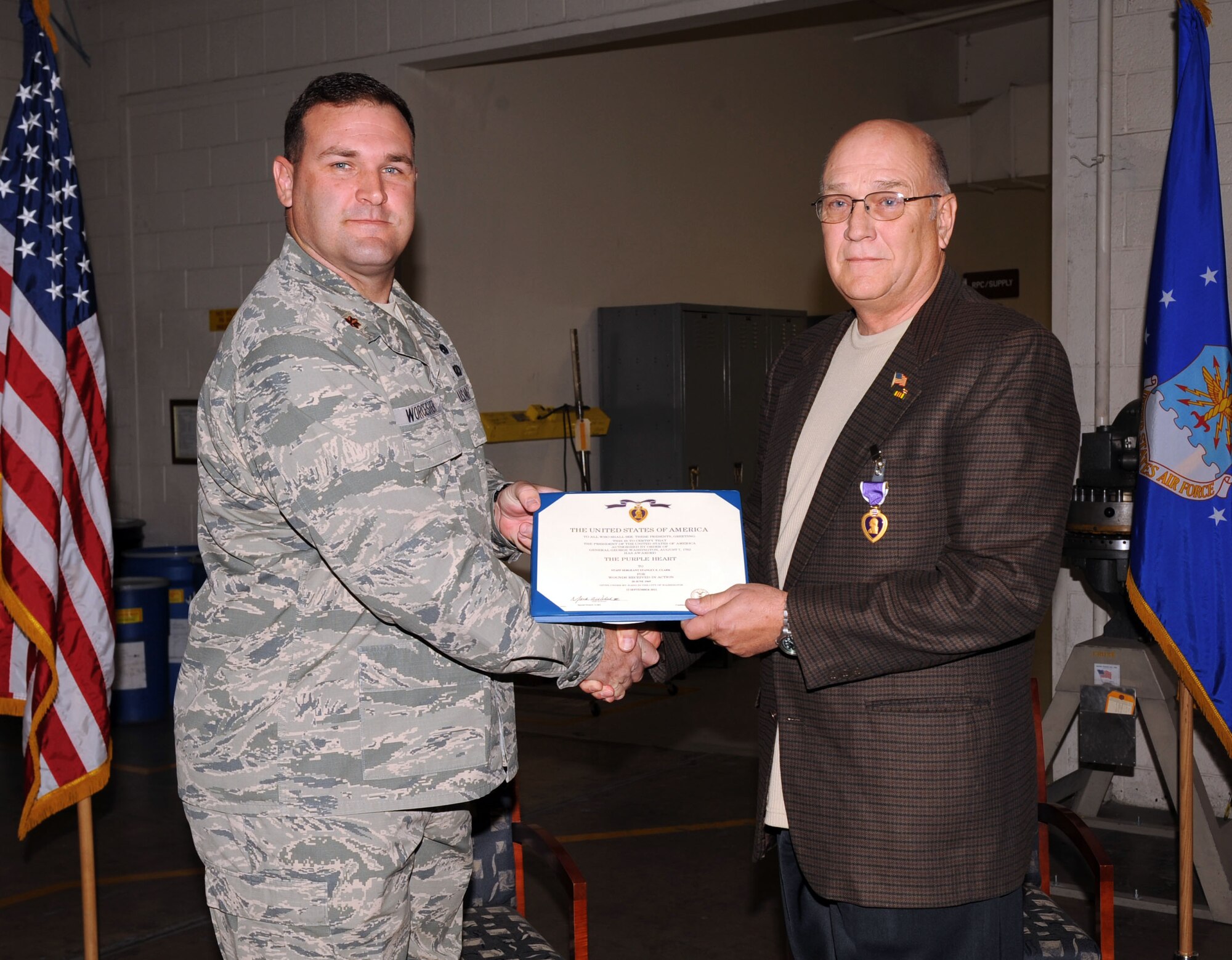 U.S. Air Force Maj. Richard Worcester, 355th Equipment Maintenance Squadron commander, presents the Purple Heart to Stanley Clark on Davis-Monthan Air Force Base, Ariz., Feb. 20, 2013. Clark was awarded the decoration for injuries he received during the Vietnam War. (U.S. Air Force photo by Senior Airman Timothy Moore/Released)
