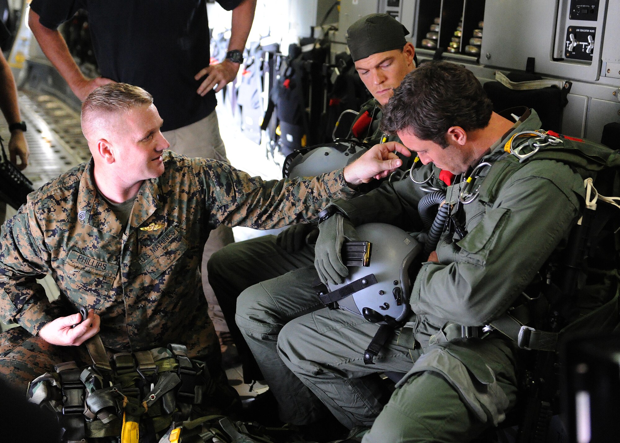 U.S. Marine Corps SSGT John Phillips, Special Operations Command, Pacific, parachute rigger, helps “Hawaii Five-0,” actors Alex O’Loughlin (right) and Alan Ritchson (center) adjust their parachute straps aboard a C-17 Globemaster at Joint Base Pearl Harbor-Hickam, Feb. 21, 2013.  The crew and cast were on scene to shoot a portion of an upcoming episode. (U.S. Air Force photo/Tech. Sgt. Jerome S. Tayborn)