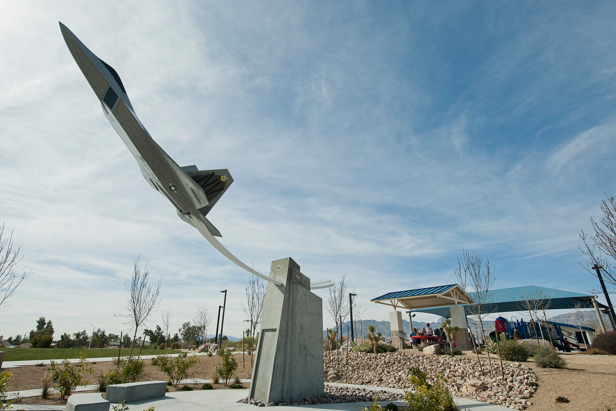 The F-22 Raptor replica is unveiled as the visual centerpiece of The Thunderbird Family Sports Complex Feb. 16, 2013. The aircraft, appearing to fly above a monument plaza with contrail-shaped curved steel beams, is anchored in a concrete base providing support. The Raptor was selected due to its use in the 57th Wing at Nellis Air Force Base and pays tribute to the United States Air Force and all military families in the Las Vegas valley. Digital Design Group provided the F-22 Raptor aircraft. (U.S. Air Force photo by Lawrence Crespo)
