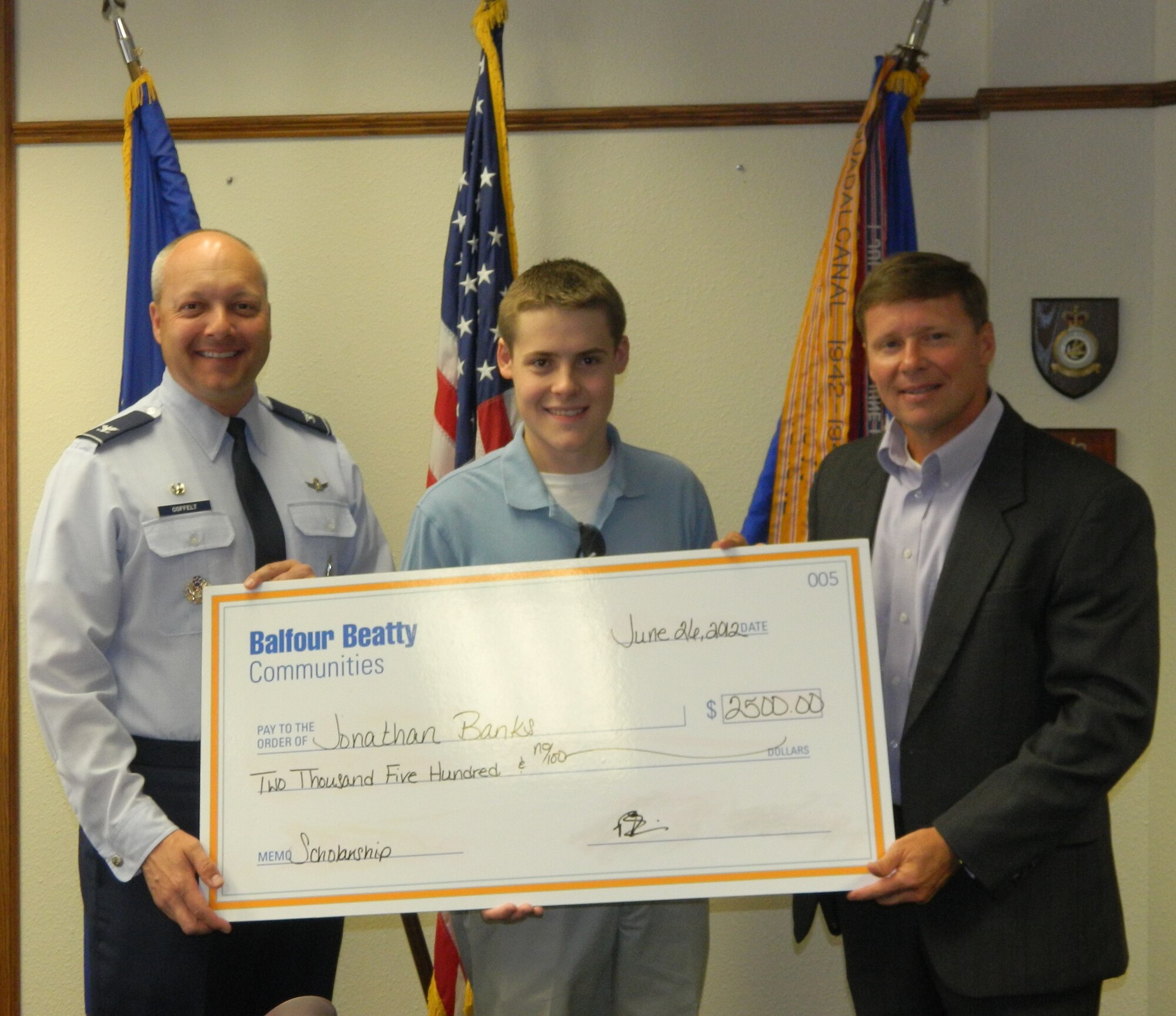 Col. Christopher Coffelt, 90th Missile Wing commander, and Barrett Larwin, Western Group Housing, LP regional vice-president, present a scholarship check to Jonathan Banks, son of Chief Master Sgt. Justin Banks, 90th Security Forces Squadron, June 26, 2012, after he was awarded last year’s Balfour Beatty Communities Foundation Academic Scholarship to Children of Military Housing Residents. To apply for this year’s scholarship, visit www.bbcommunitiesfoundation.org. The application deadline is April 15. (Courtesy photo)
