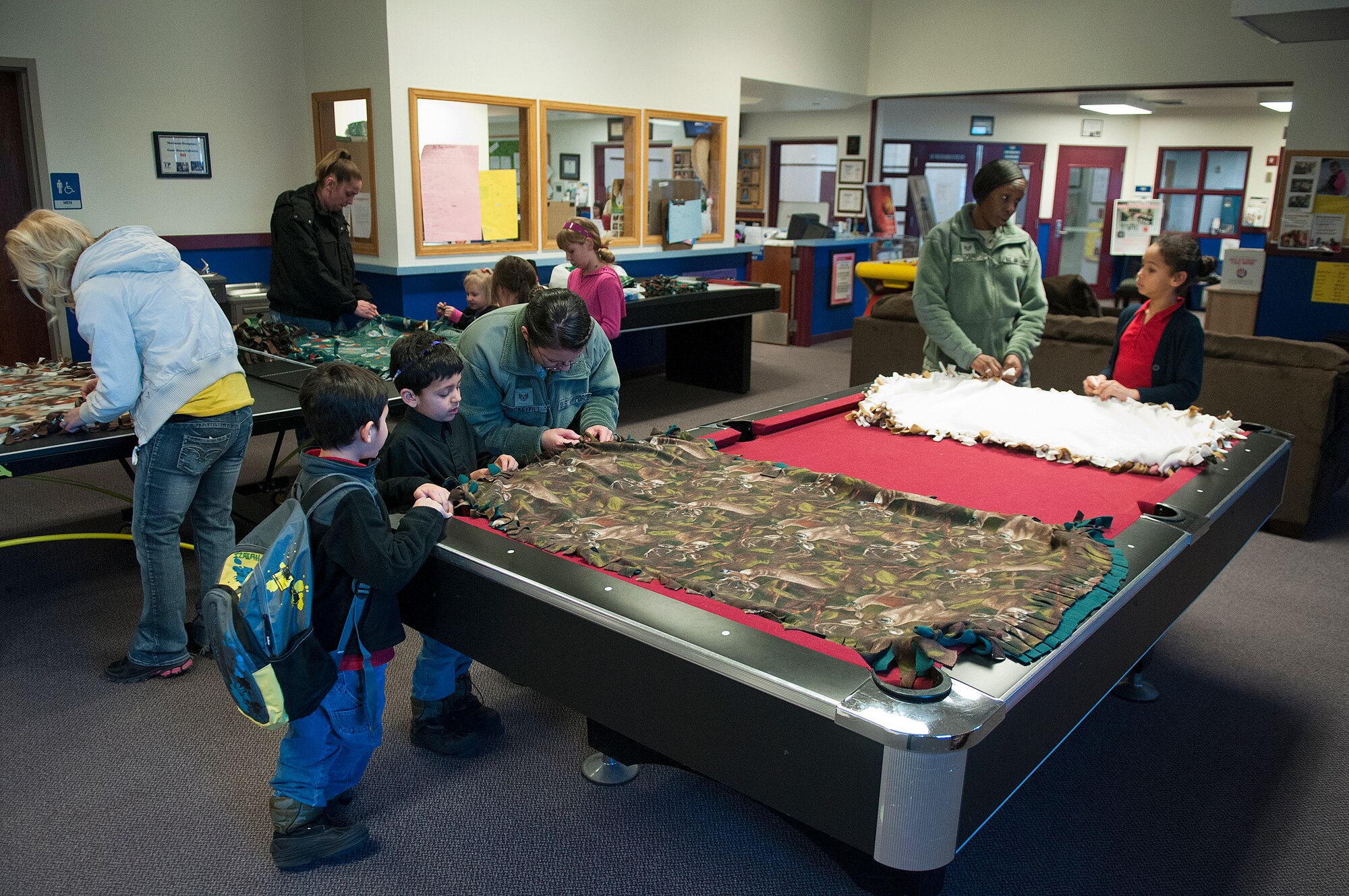 F. E. Warren Air Force Base youths, their parents and youth center staff work on lap blankets in the base youth center Feb. 14. Making the blankets, for donation to the Cheyenne Veteran Affairs Medical Center’s nursing facility was part of a community service project sponsored by the youth center. According to Tammy Stone, youth center director, seven children, along with youth center staff, delivered eight blankets to the VA the next day. 
Stone said it is the center’s goal to get the children involved in a community service project every month. “We wanted to get the kids more involved in the community.” Amanda Showmaker, youth program assistant, said. “They can do something nice and see how nice it is to give.” (U.S. Air Force photo by R.J. Oriez)