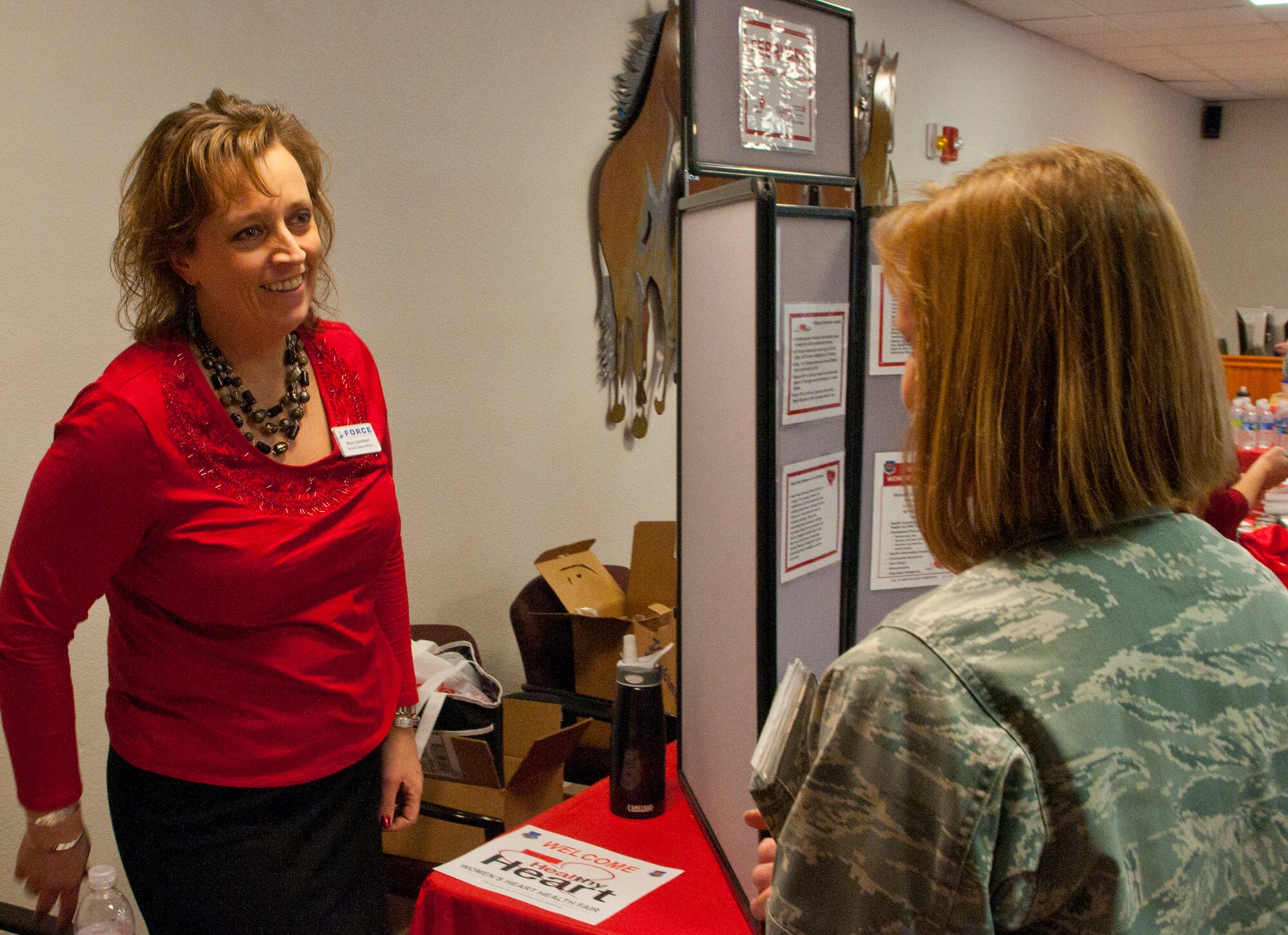 Mary Jacobsen, 90th Force Support Squadron school liaison officer, discusses Airman and Family Readiness Center programs with Maj. Jutta Arkan, 90th Force Support Squadron deputy commander, in the 90th Medical Group Clinic Feb. 14. Part of the focus of the women’s heart health event was increasing awareness of community resources to the base population. (U.S. Air Force photo by Airman 1st Class Jason Wiese)