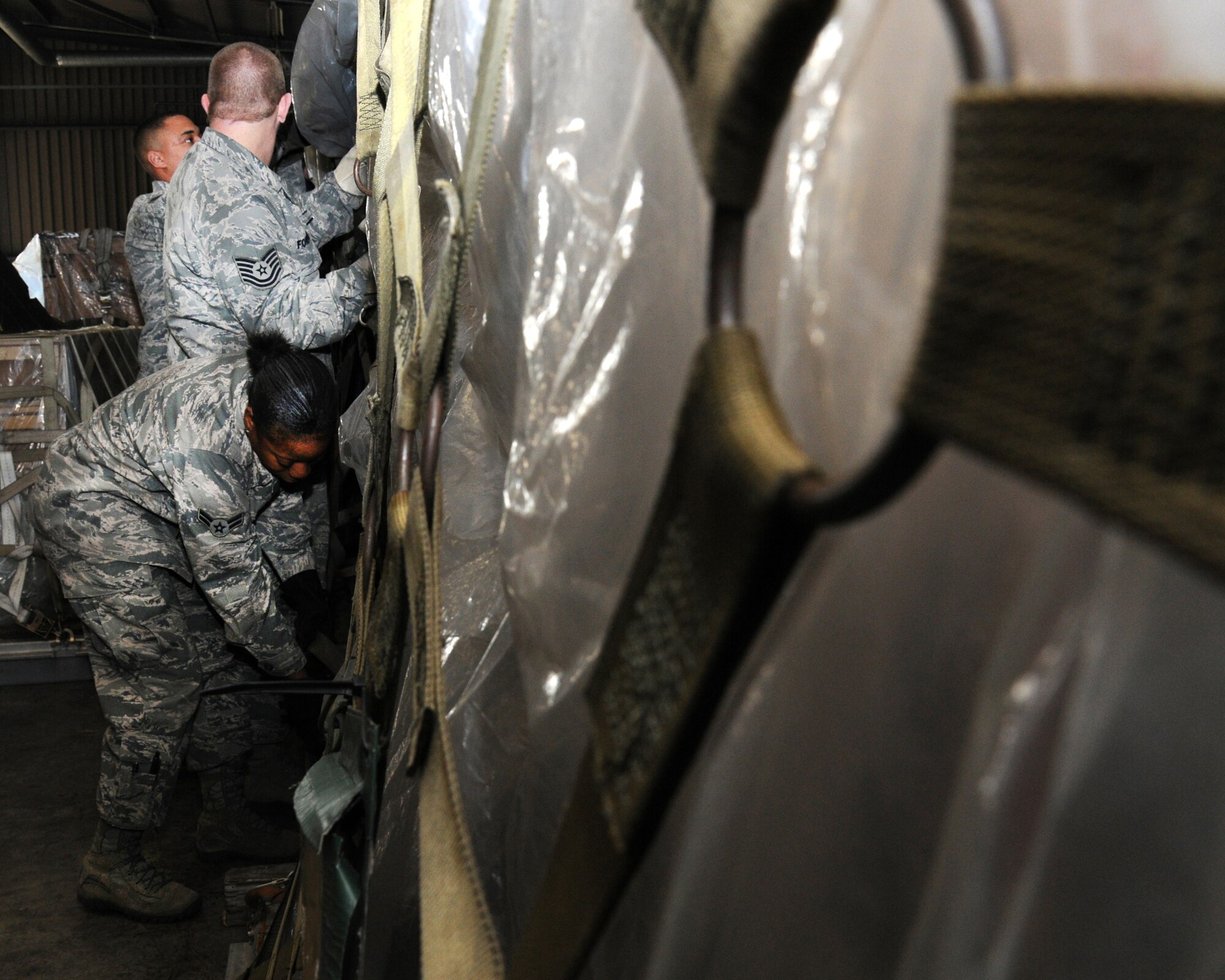 100th Logistics Readiness Squadron Mobility Readiness Spares Package shop members work together to net a pallet of cargo Feb. 19, 2013, at RAF Mildenhall, England. The MRSP is a part of the 100th LRS Material Management Flight. (U.S. Air Force photo by Gina Randall/Released)