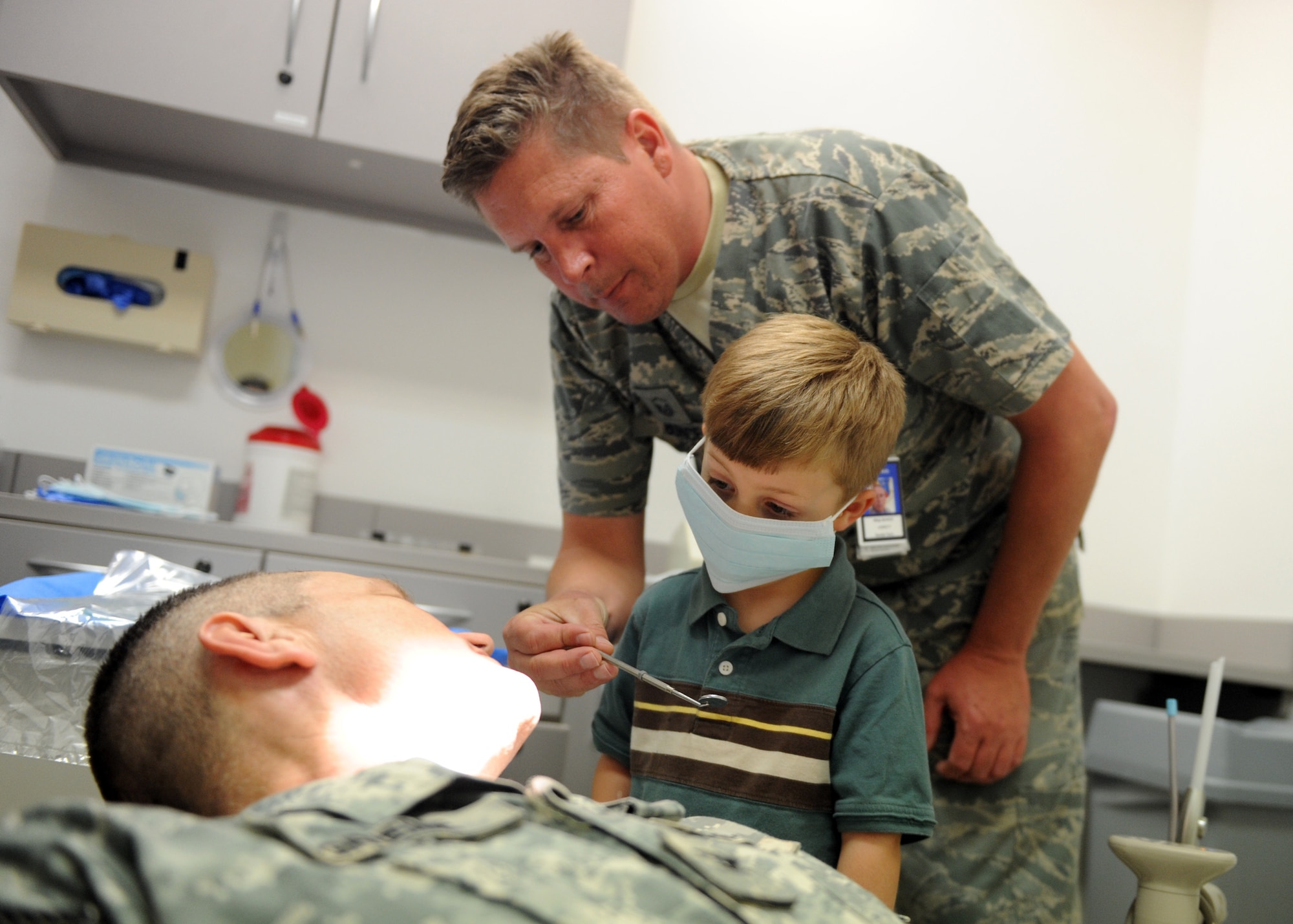 SOUTHWEST ASIA – Jacob prepares to look at his dad’s teeth with the help of Master Sgt. James Bunce, 379th Expeditionary Medical Group dental technician on Feb. 17.  Col. Wayne Grieme Jr., U.S. Army Support Group commander, brought his son to the 379th EMDG Clinic as part of the clinic’s support of National Children’s Dental Health Month.  After Jacob was finished playing dentist, he received a dental exam by the dentist, Lt. Col. Son Vu.  (U.S. Air Force photo/Senior Airman Joel Mease)
