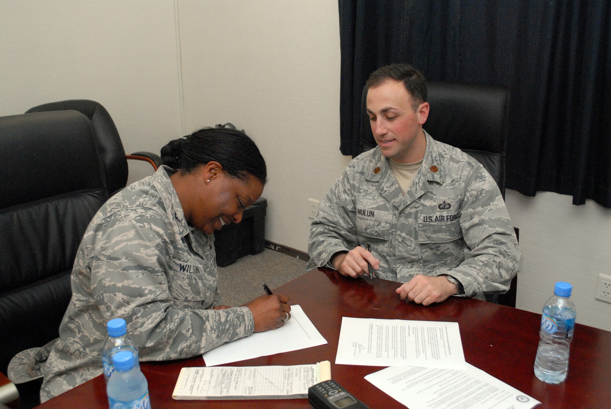 SOUTHWEST ASIA -- 379th Expeditionary Support Group Commander Col. Stephanie Wilson signs a letter authorizing her to  make one-time purchase on behalf of the contracting officer, on right, 379th Expeditionary Contracting Squadron Commander Maj. Richard Hulun, Feb. 15. The 379th ECONS serves the 379th Air Expeditionary Wing in Southwest Asia by managing the purchasing and acquisition for materiel needed to keep the mission properly supplied. (U.S. Air Force photo/Master Sgt. Christian Michael)