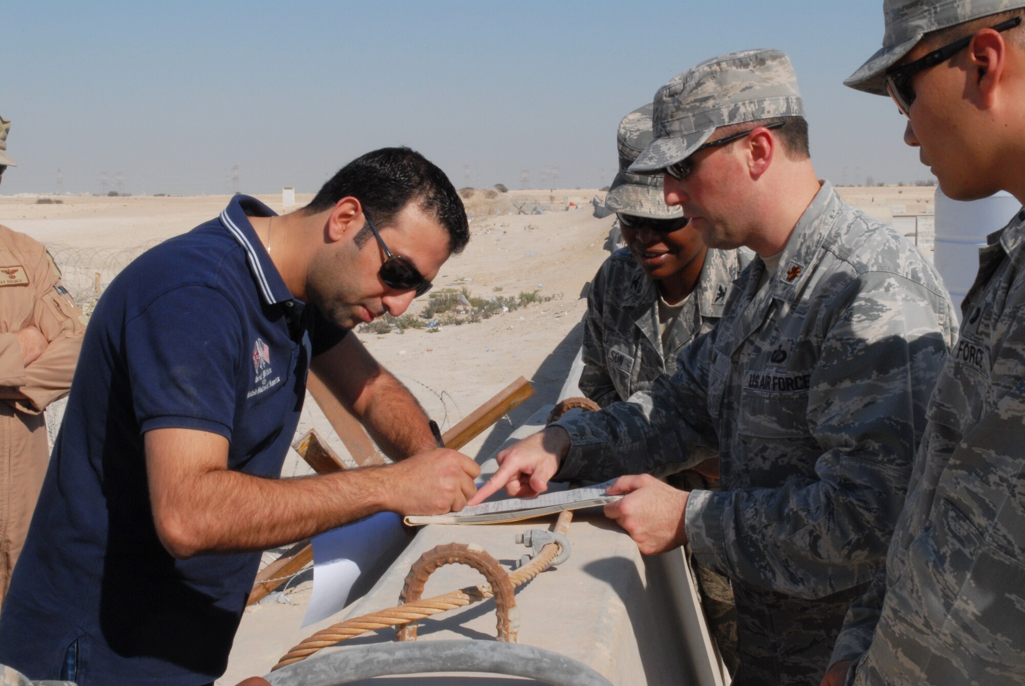 SOUTHWEST ASIA -- A member of the Host Nation Coordination Cell serves as an intermediary for a purchase of toner ink by appointed-purchasing officer, 379th Expeditionary Support Group Commander Col. Stephanie Wilson, who watches while 379th Expeditionary Contracting Squadron Commander Maj. Richard Hulun helps him and 1st Lt. David Won, base support flight commander, looks on, Feb. 15. The 379th ECONS serves the 379th Air Expeditionary Wing in Southwest Asia by managing the purchasing and acquisition for materiel needed to keep the mission properly supplied. (U.S. Air Force photo/Master Sgt. Christian Michael)
