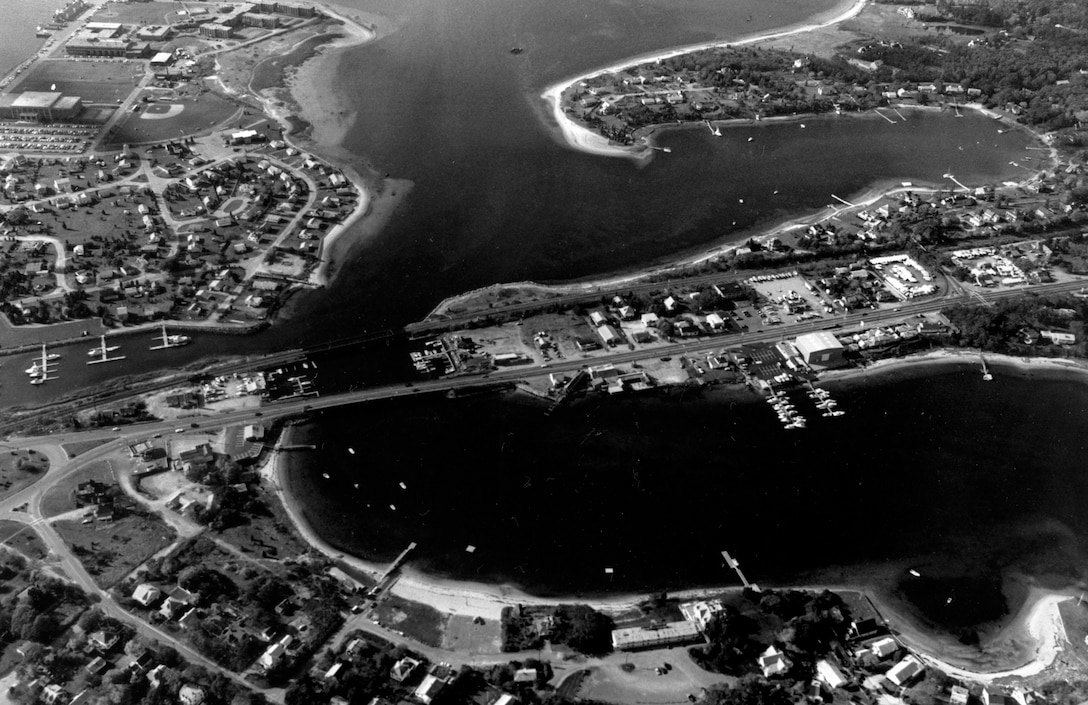 Aerial view of Buttermilk Bay. Buttermilk Bay is located in the upper reaches of Buzzards Bay, between Bourne and Wareham, at the southern end of the Cape Cod Canal. Access to Buttermilk Bay is through a two-mile natural channel extending from Buzzards Bay past Butler Cove, Bourne and Wareham, MA. Photograph taken Nov. 1987.