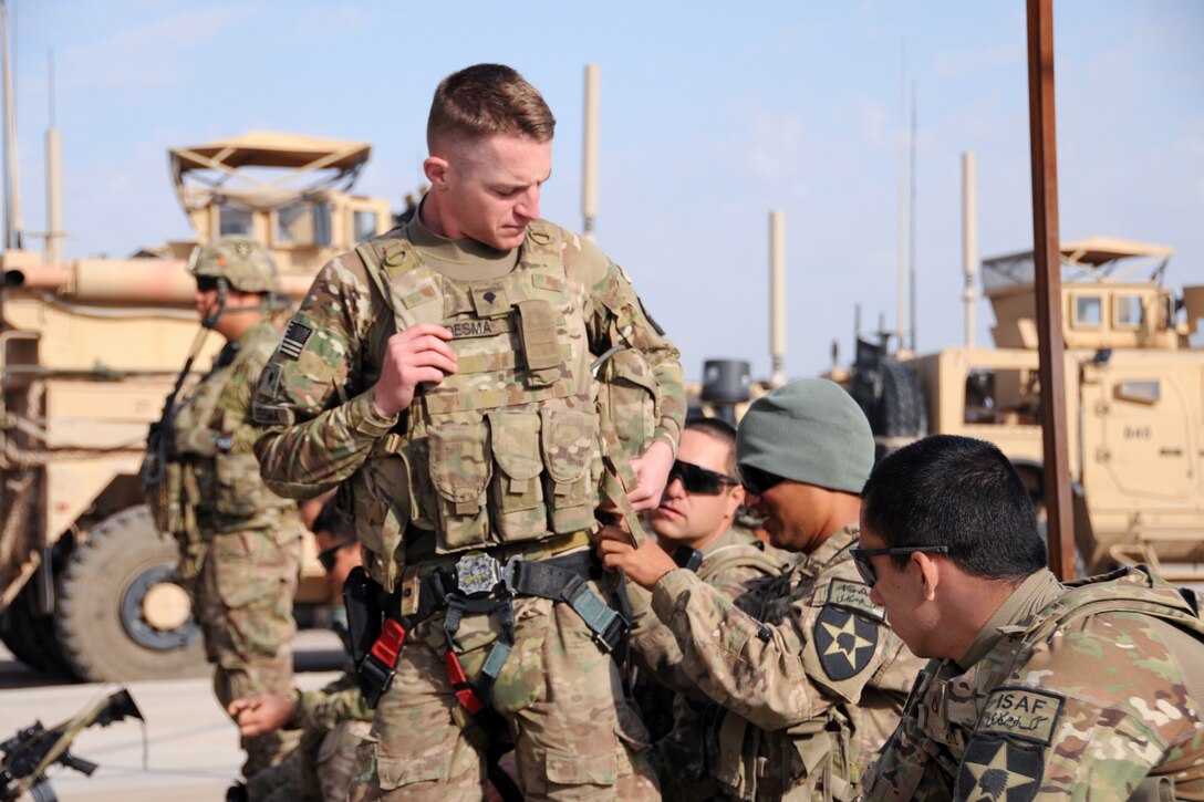 U.S. Army Spc. Mario Chavez, right with hat, assists fellow team member, U.S. Army Spc. Justin Ledesma, center, with his gunner's restraint harness before departing Forward Operating Base Farah for a mission in Farah City, Afghanistan, Feb. 18, 2013. Chavez and Ledesma are assigned to assigned to Provincial Reconstruction Team Farah. Team leaders met with the Farah provincial govenor's staff at the goverment compound in Farah City to discuss ongoing coordination efforts in the province.
