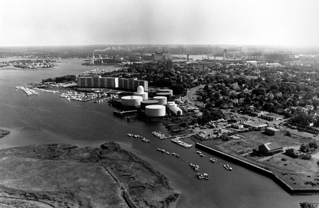 Aerial view of Weymouth Town River. Town River (before 1965): Town River, which lies entirely within Quincy city limits, is a tidal river about two miles long that empties into Weymouth Fore River between Quincy Point and Germantown Point. Initial work on Town River, completed in 1906, consisted of a channel four feet deep extending westward from the Weymouth Fore River, MA. In 1965 the two projects were combined and modified to facilitate navigation. Photo was taken in Oct. 1987.
