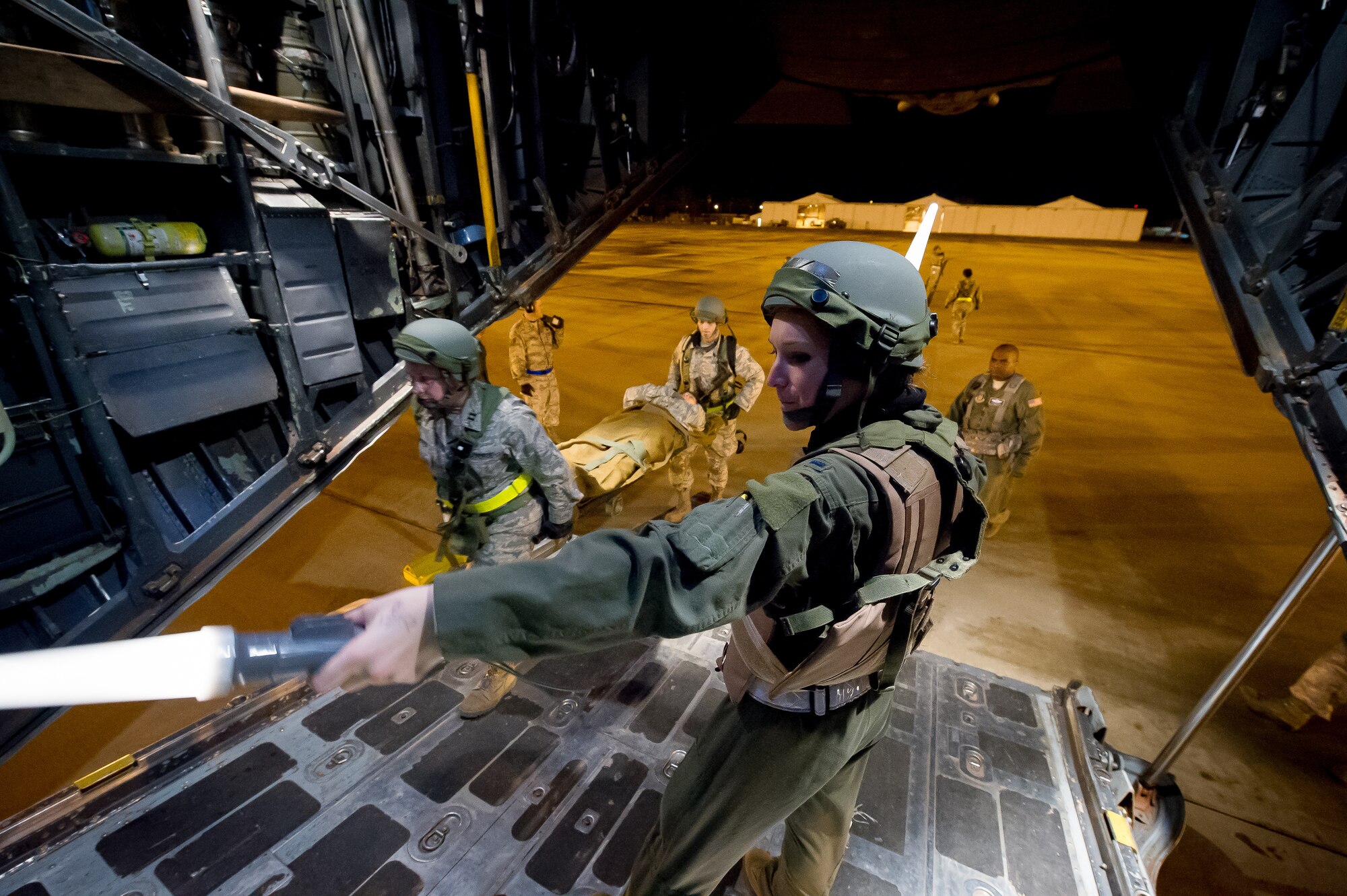 U.S. Air Force 1st Lt. Erin Wood, 18th Aeromedical Evacuation Squadron medical crew director, Kadena Air Base, Japan, uses hand signals to control the loading of simulated patients onto a C-130 Hercules aircraft in Alexandria, La., Feb. 22, 2013, in support of Joint Readiness Training Center aeromedical evacuation training. Service members at JRTC 13-04 are educated in combat patient care and aeromedical evacuation in a simulated combat environment. (U.S. Air Force photo by Tech. Sgt. John R. Nimmo Sr.)