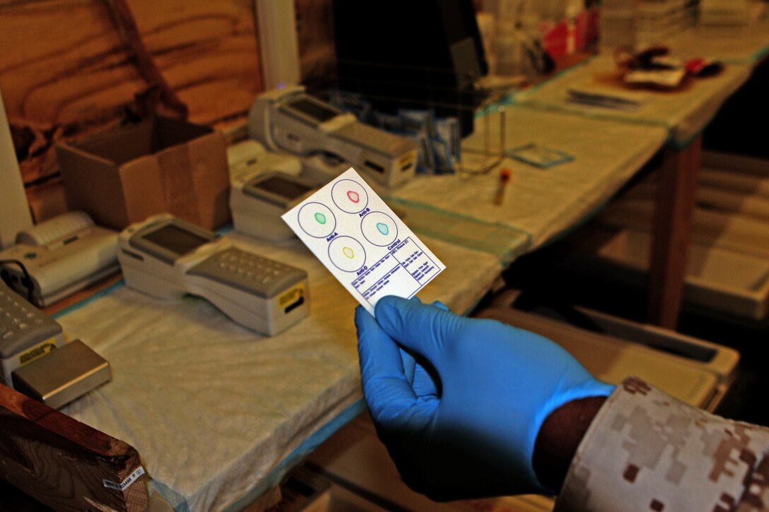 HM2 Keron Liverpool, a laboratory technician with Surgical Platoon, Combat Logistics Regiment 2, holds out a blood-type card, which is used to conduct a blood test.  Within a minute he will be able to determine the patient's blood type.  