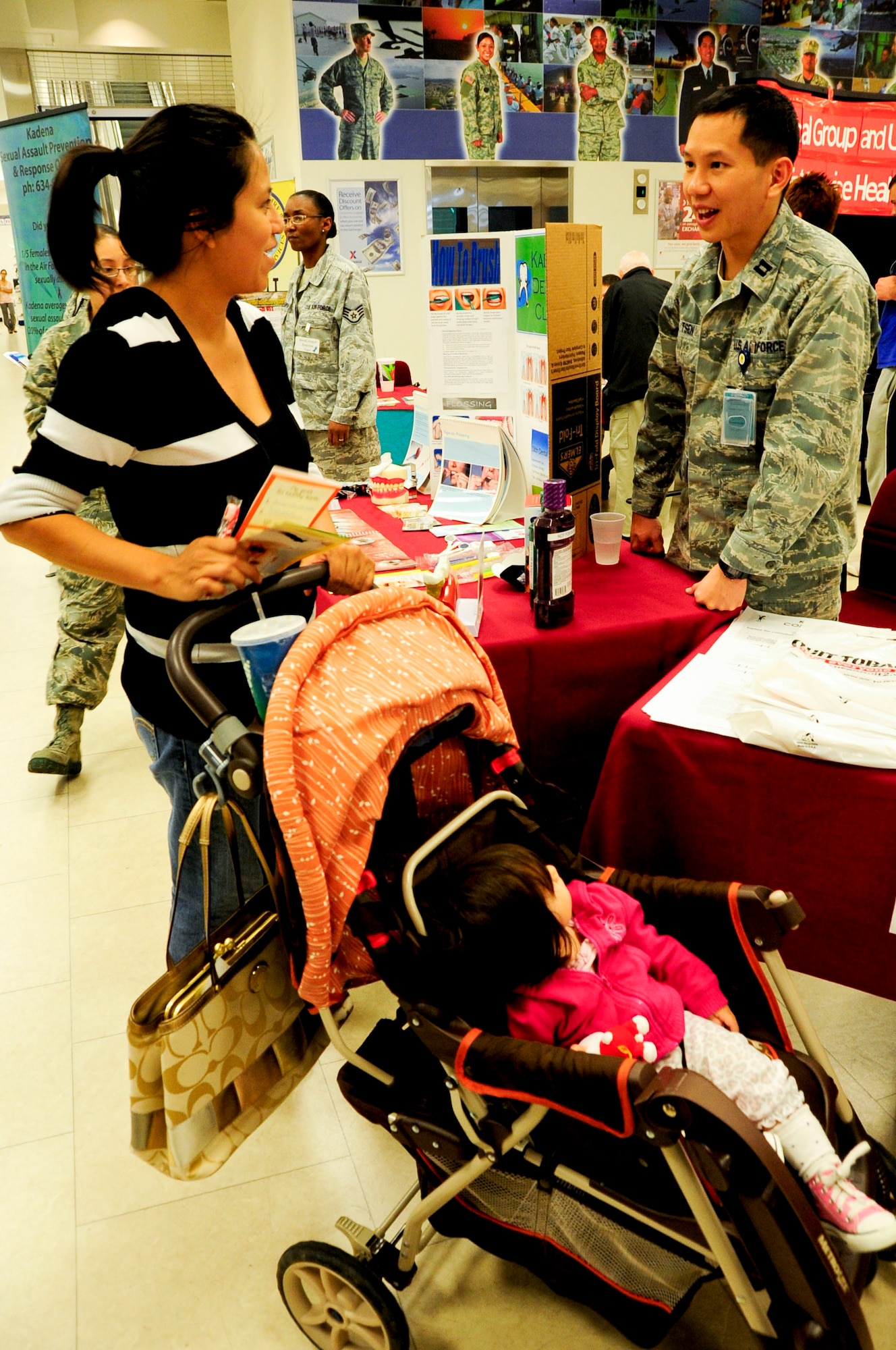 Maria Teichmann, military spouse, receives information for her daughter, Lydia Teichmann, from U.S. Air Force Capt. Chung Tsen, 18th Medical Group general dentist, during a Joint Services Health Promotion Fair at the Exchange on Kadena Air Base, Japan, Feb. 21, 2013. The dental booth informed people about the proper ways of brushing teeth and flossing and provided dental information for children. The 10-booth health fair was the first joint service effort between Kadena and Camp Lester and provided information on programs including dental, alcohol and drug abuse prevention and treatment and disease management. (U.S. Air Force photo/Staff Sgt. Darnell T. Cannady)