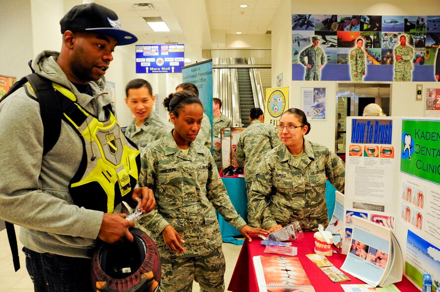 U.S. Air Force Staff Sgt. Adom Randolph, 718th Aircraft Maintenance Squadron assistant NCO in charge of 961st Aircraft Mainteance Unit combat-oriented supply operations, checks out the dental booth and receives information from Tech. Sgt. Jennifer Randolph, of the 18th Aerospace Medicine Squadron, and Staff Sgt. Sarai Gapetz, of the 18th Dental Squadron, during a Joint Services Health Promotion Fair at the Exchange on Kadena Air Base, Japan, Feb. 21, 2013. The dental booth informed members about the proper ways of brushing teeth and flossing and provided dental information for children. (U.S. Air Force photo/Staff Sgt. Darnell T. Cannady)